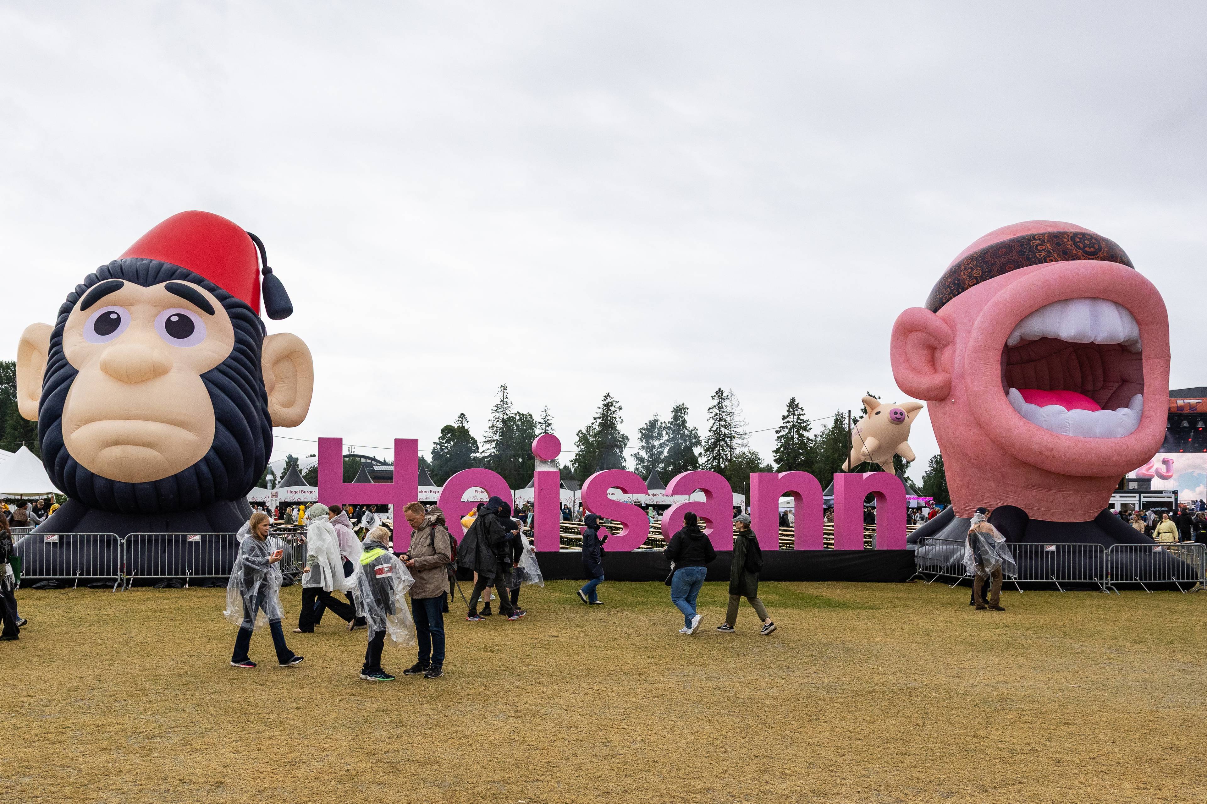 Publikum ved store oppblåsbare figurer med teksten Heisann på en festivalarena. (Bildebeskrivelsen er laget av en KI-tjeneste)