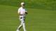 DYLAN BUELL / GETTY IMAGES NORTH AMERICA,NTB En golfspiller i hvit caps og polo t-skjorte går på en gressbane. Mannen har på seg grå bukser og hvite sko. Han holder en golfkølle. (Bildebeskrivelsen er laget av en KI-tjeneste)