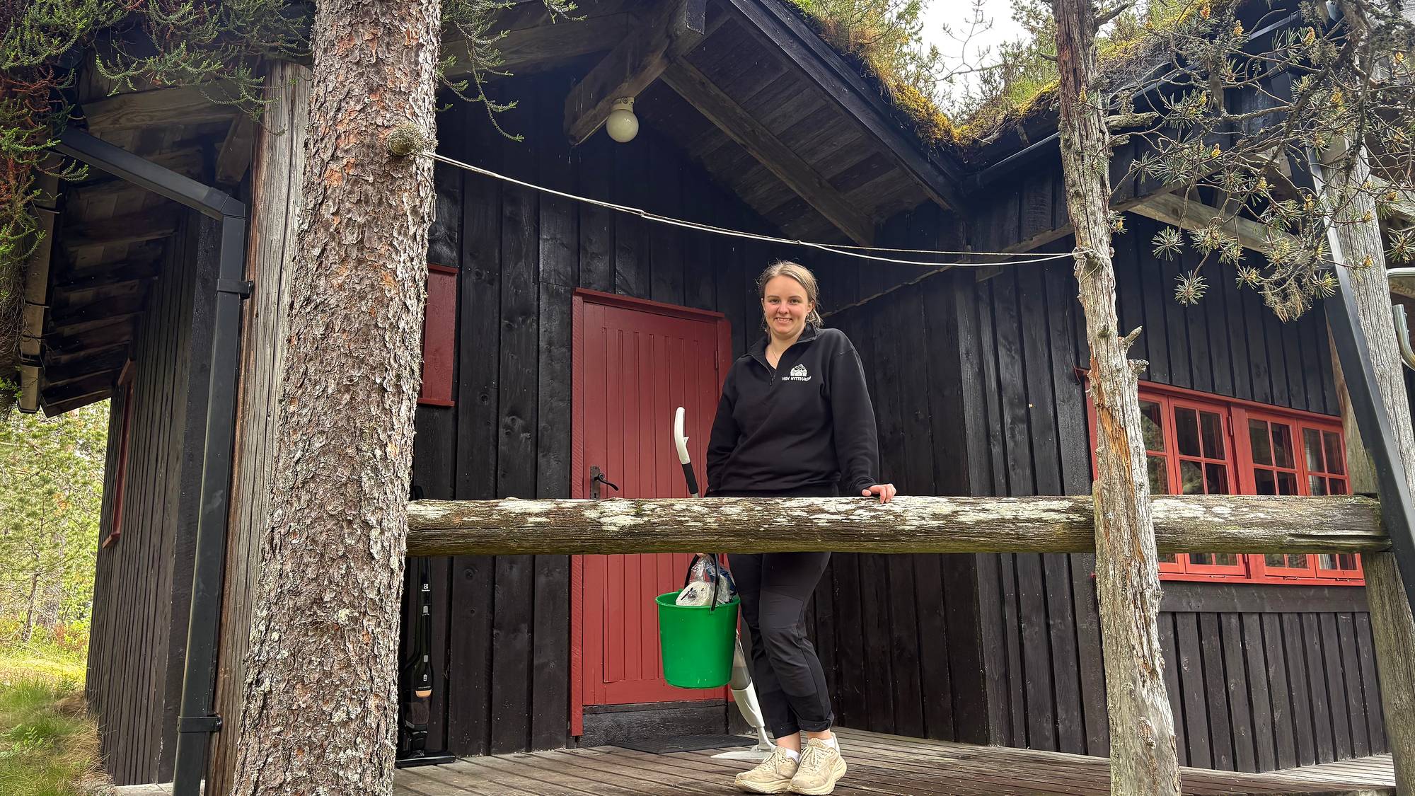 ei dame står ved ei hytte 