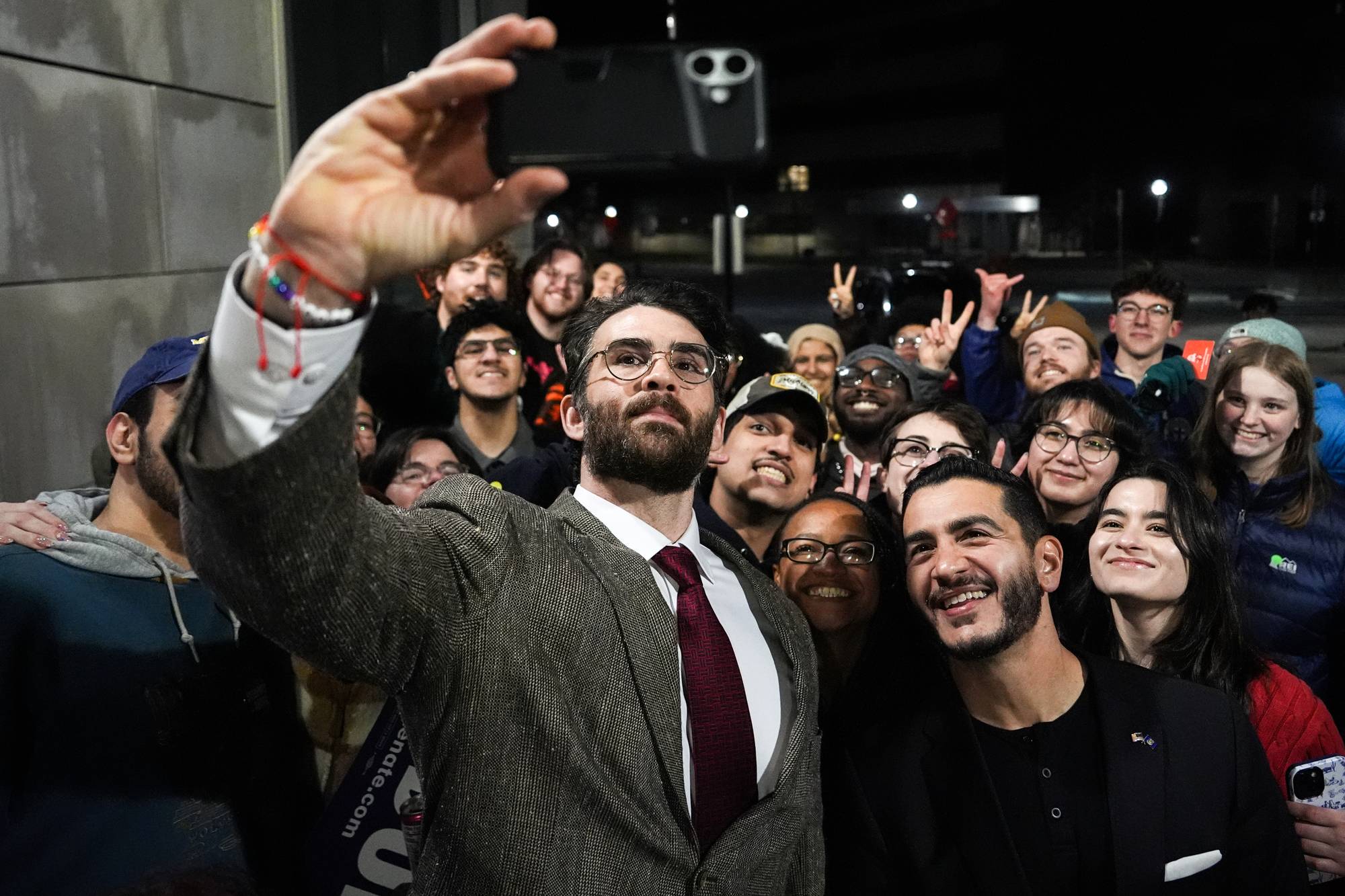 Streamer Hasan Piker, left, and Abdul El-Sayed, a progressive candidate in the Democratic primary for U.S. Senate in Michigan, center right, take a selfie with young fans following a campaign event.