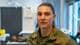 Reidar Gregersen / NRK En kvinne iført militæruniform står i et rom med medisinsk utstyr. Bak henne ses en klokke og annet helsepersonellutstyr. Omgivelsene fremstår som en klinisk setting, sannsynligvis knyttet til helsetjenester i militæret. Belysningen er naturlig fra vinduene ved siden av henne.