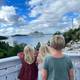 Privat Tre blondebarn, to jenter og ein gut, står på ein altan ved eit rekkverk og kikar utover mot sjøen og eit cruiseskip i det fjerne.