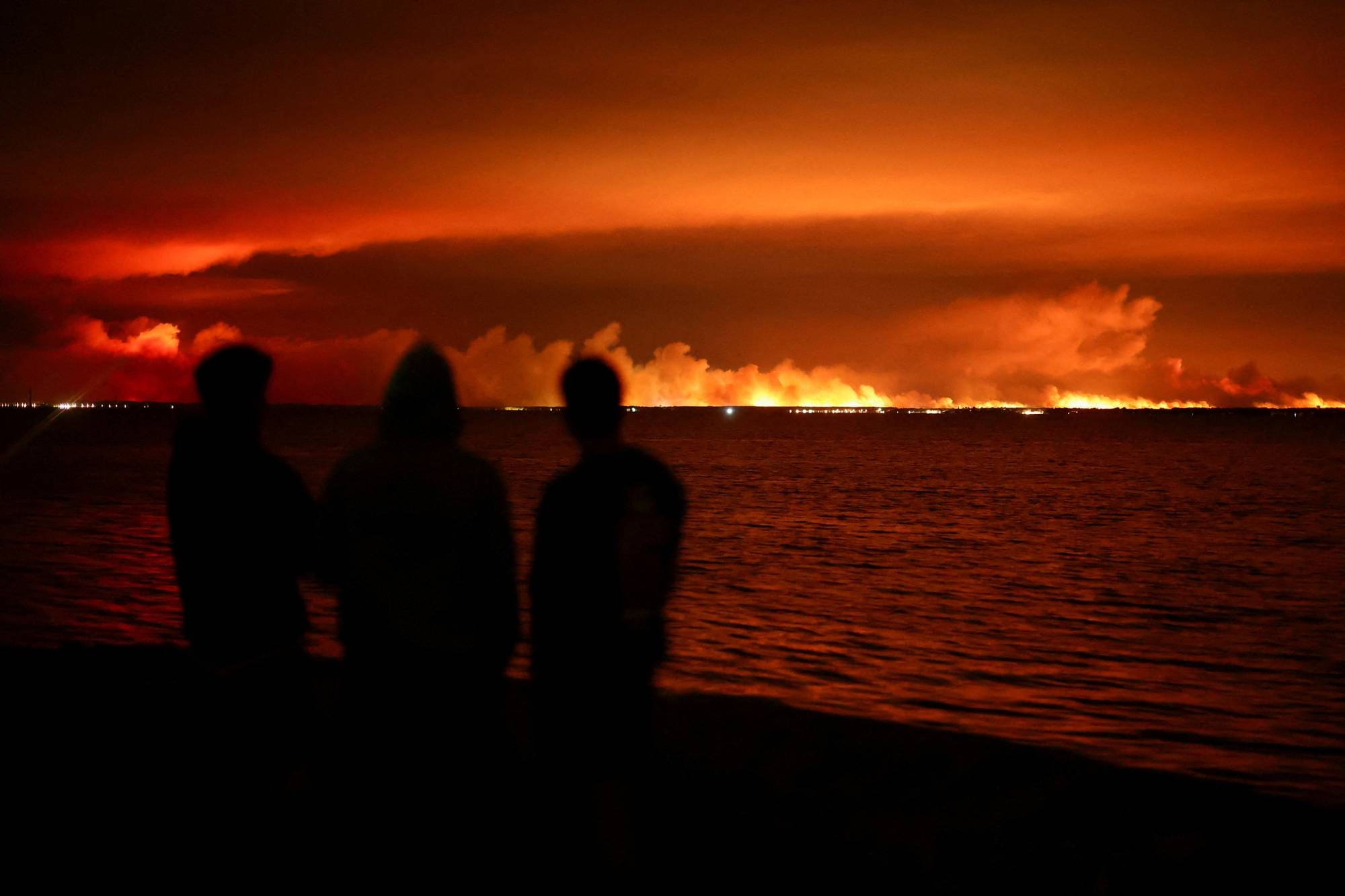 Mennesker ser på røde flammer på avstand. 
