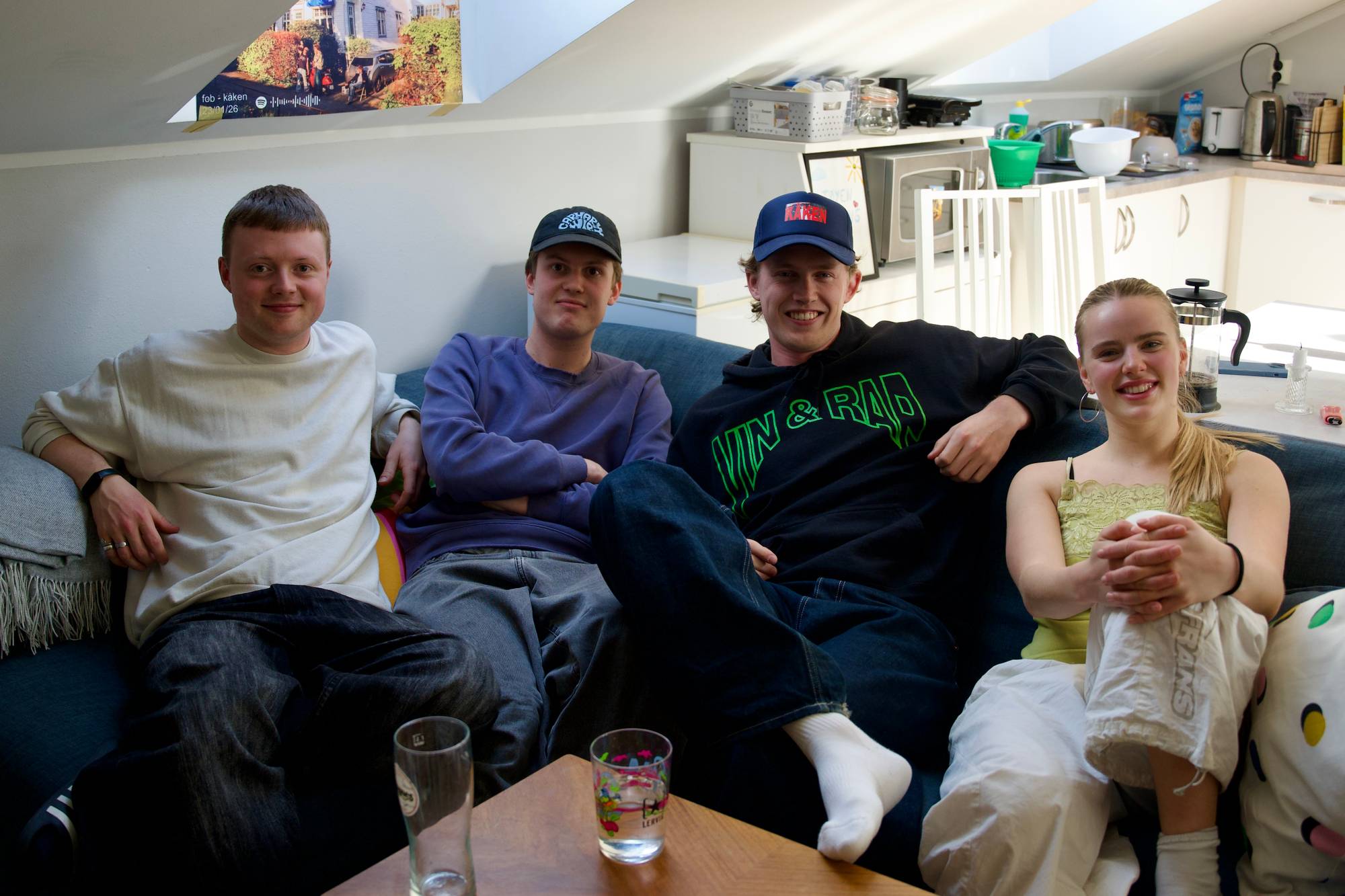 Kollektivet bestående av fire unge voksne, sitter sammen i sofaen i stua. De smiler og ser mot kamera. Fra venstre: Leon, Mikal, Jon og Marie. 