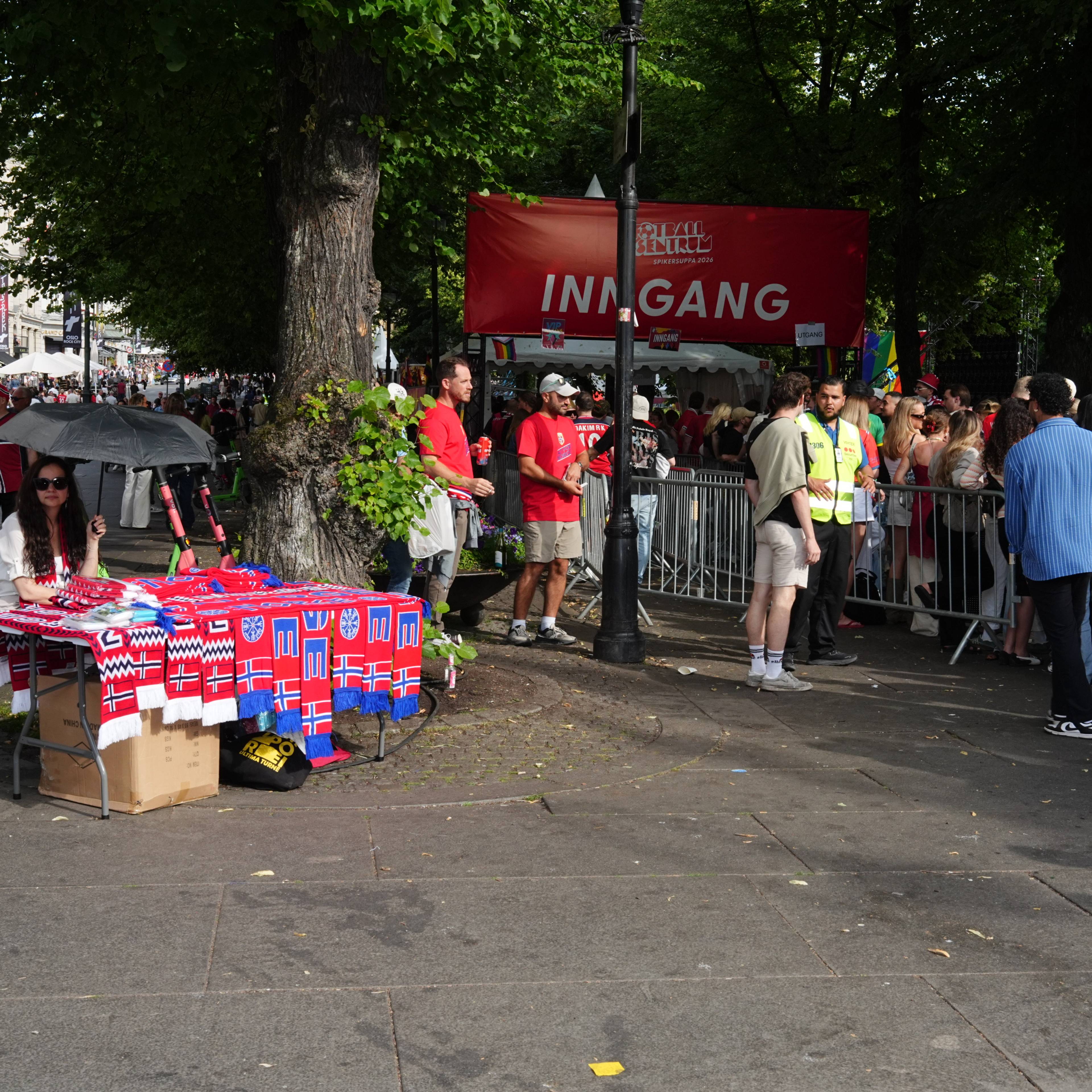 Folk står i kø ved inngangen til et arrangement i Spikersuppa, mens noen selger norske skjerf.