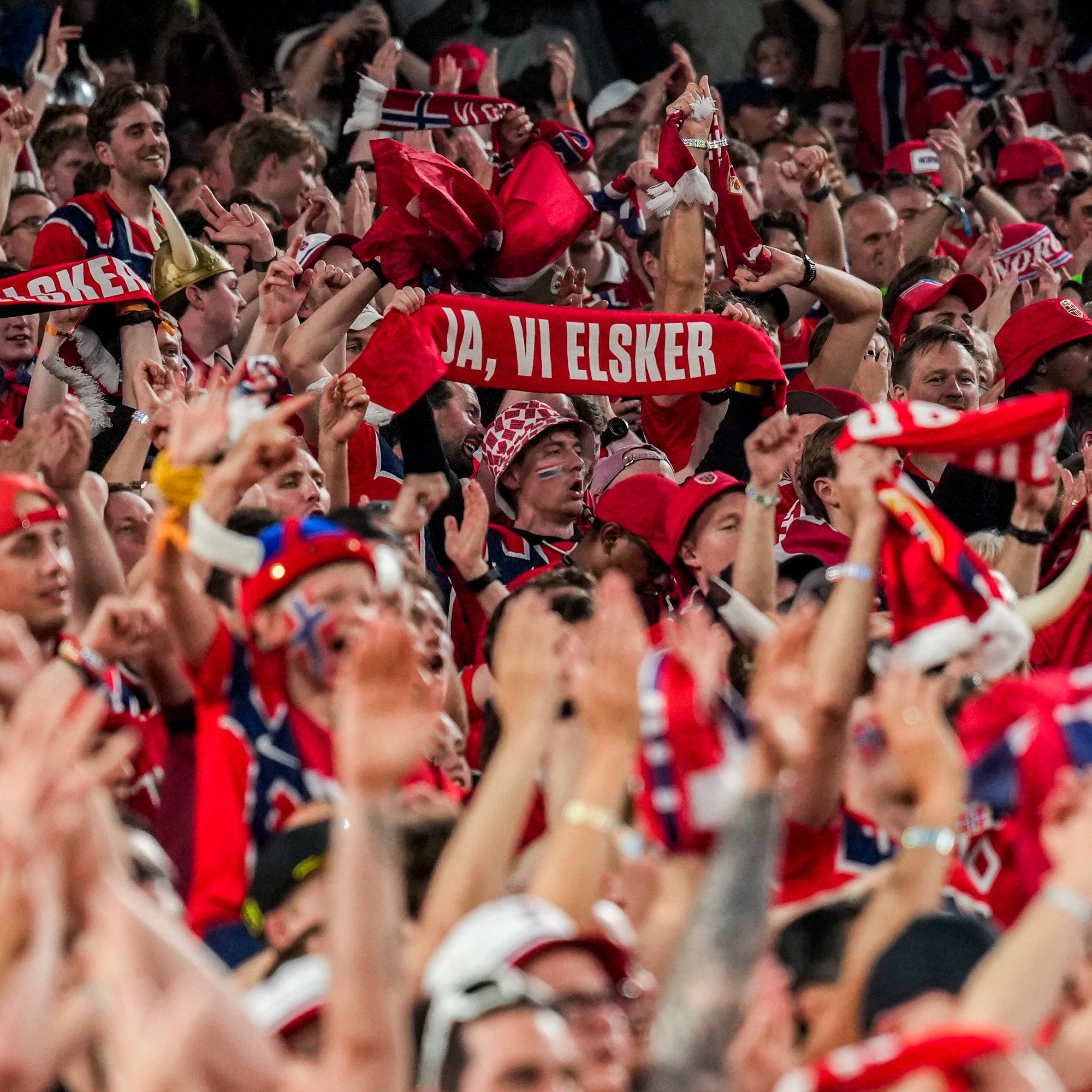 Norske supportere med skjerf over hodet. På ett står det "Ja, vi elsker". 
