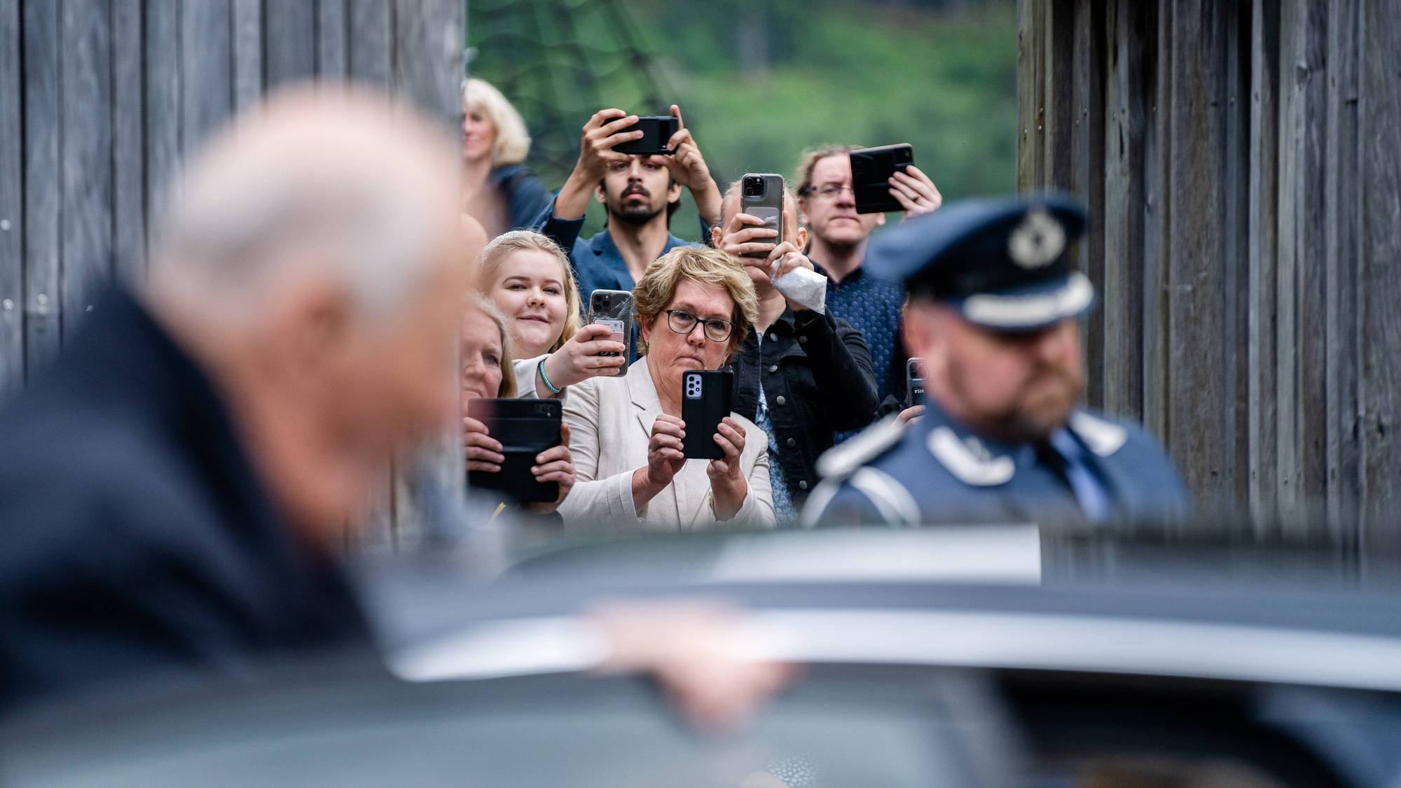 Mange mennesker står tett i tett og tar mobilbilder av kong Harald når han skal forlate Åseral 27. mai 2024