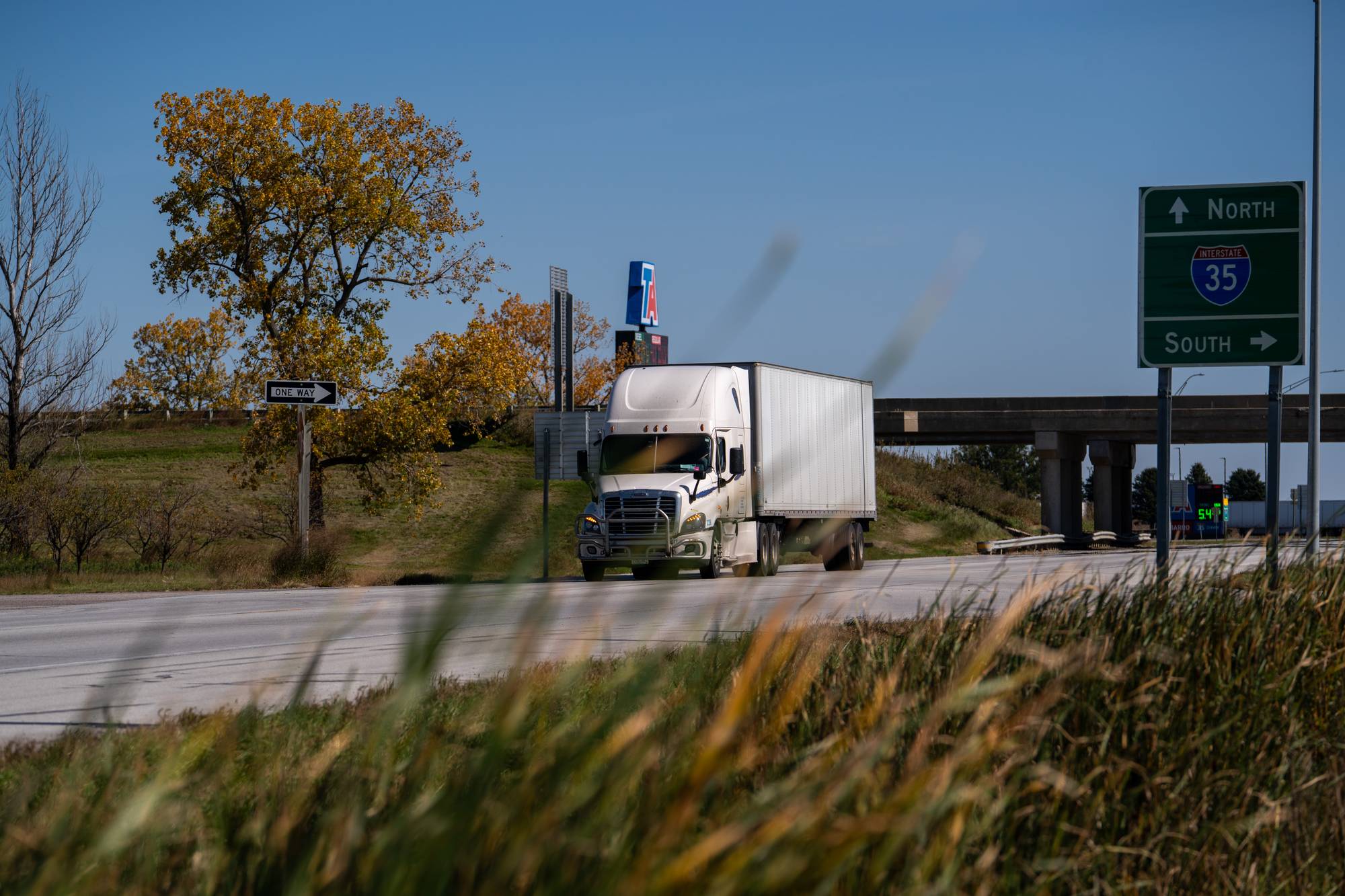 Hvit semitrailer kjører på motorvei nær et skilt for Interstate 35. (Bildebeskrivelsen er laget av en KI-tjeneste)