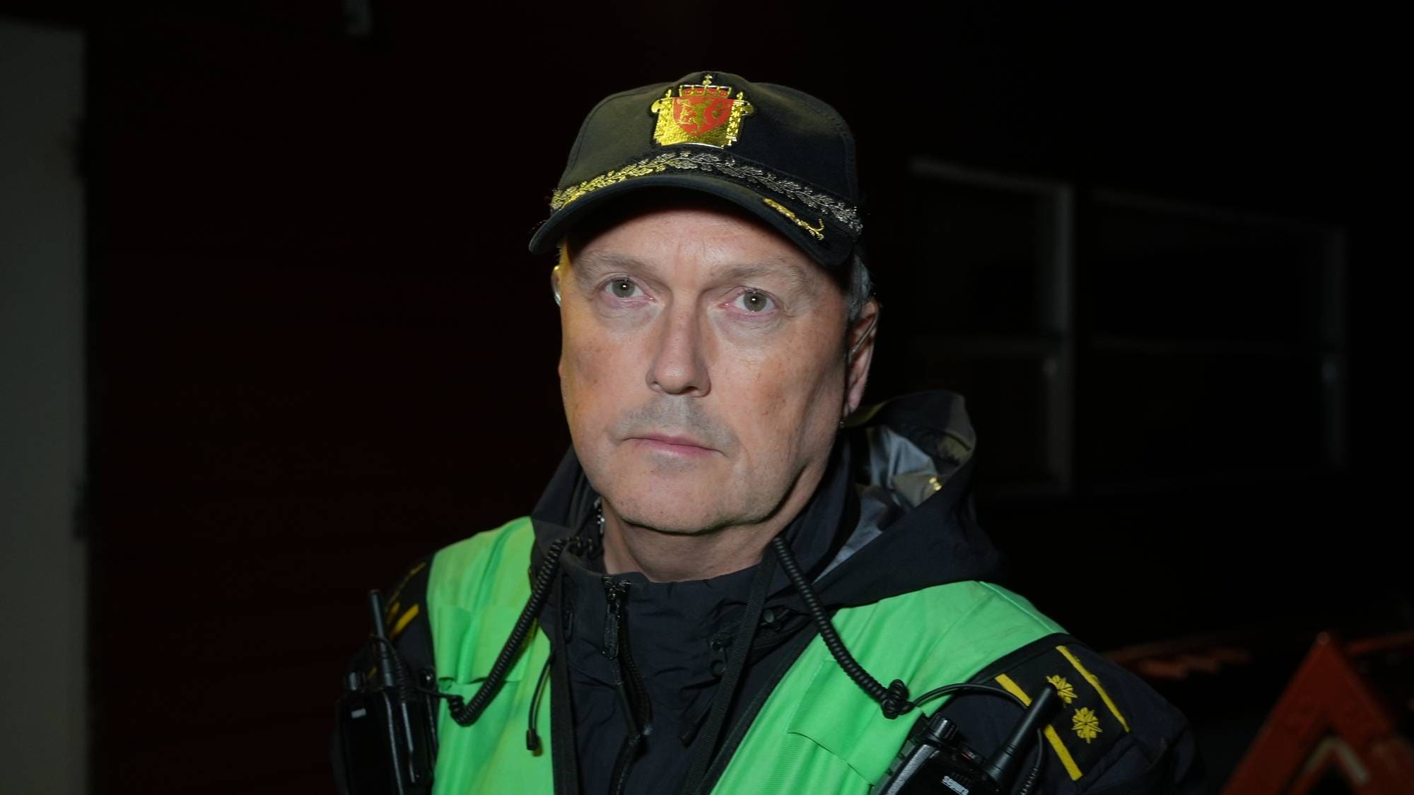 Politibetjent i uniform med grønn refleksvest og politilue med riksvåpenet. (Bildebeskrivelsen er laget av en KI-tjeneste)