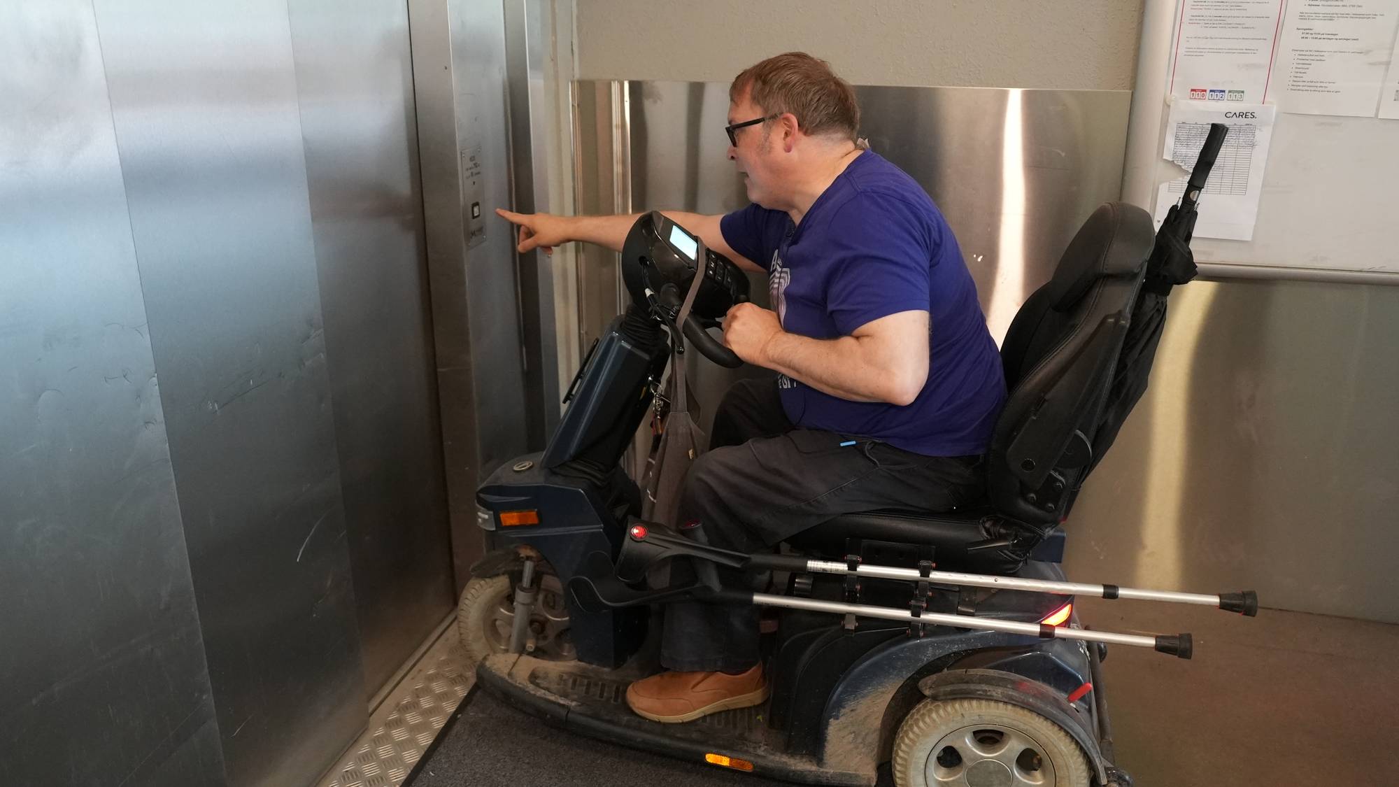 En mann trykker på en heisknapp utenfor en heis