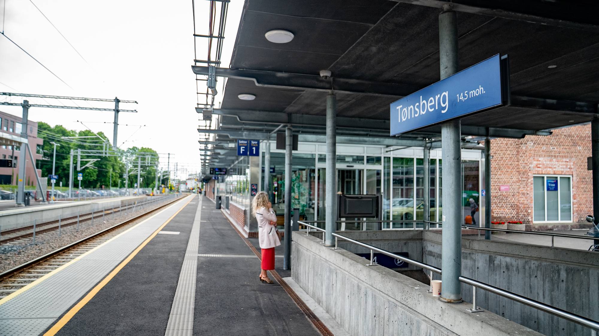 En jente som står på en plattform ved siden av en togstasjon (Bildebeskrivelsen er laget av en KI-tjeneste)