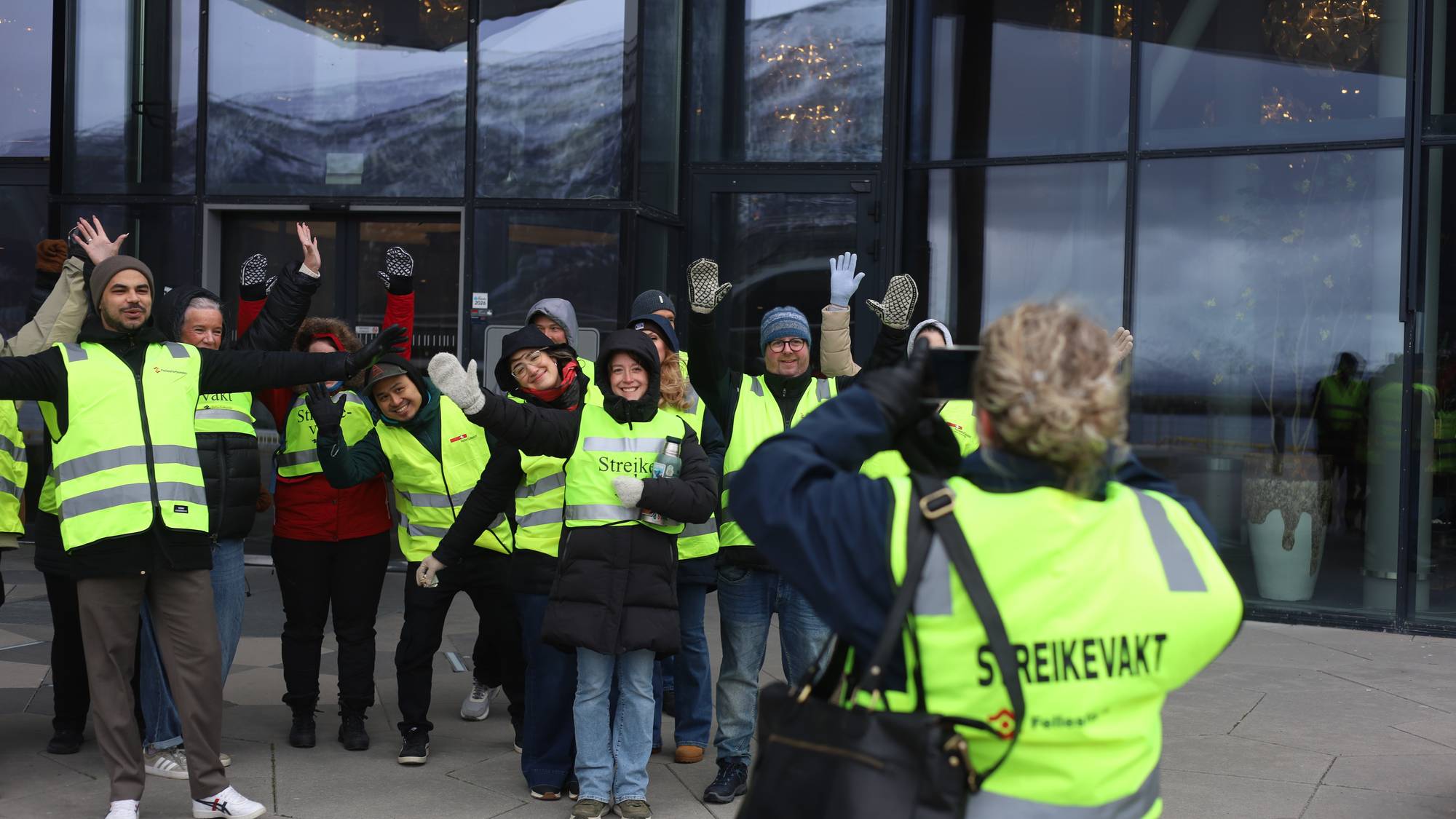 Et reflekskledd gjeng poserer foran en fotograf utenfor et hotell.