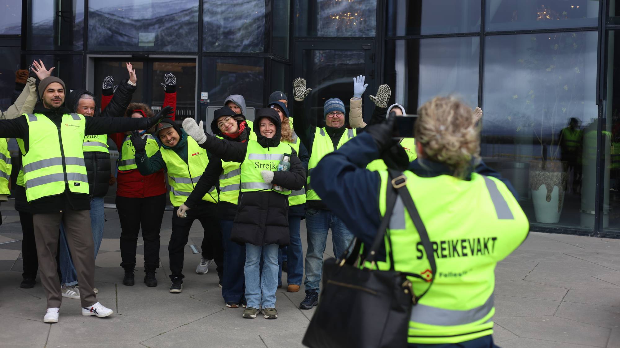 Et reflekskledd gjeng poserer foran en fotograf utenfor et hotell.