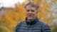 Henrik Myhr Nielsen / NRK En mann står ute i en park med gule og grønne høstblader i bakgrunnen. Han har på seg en svart, quiltet jakke.
