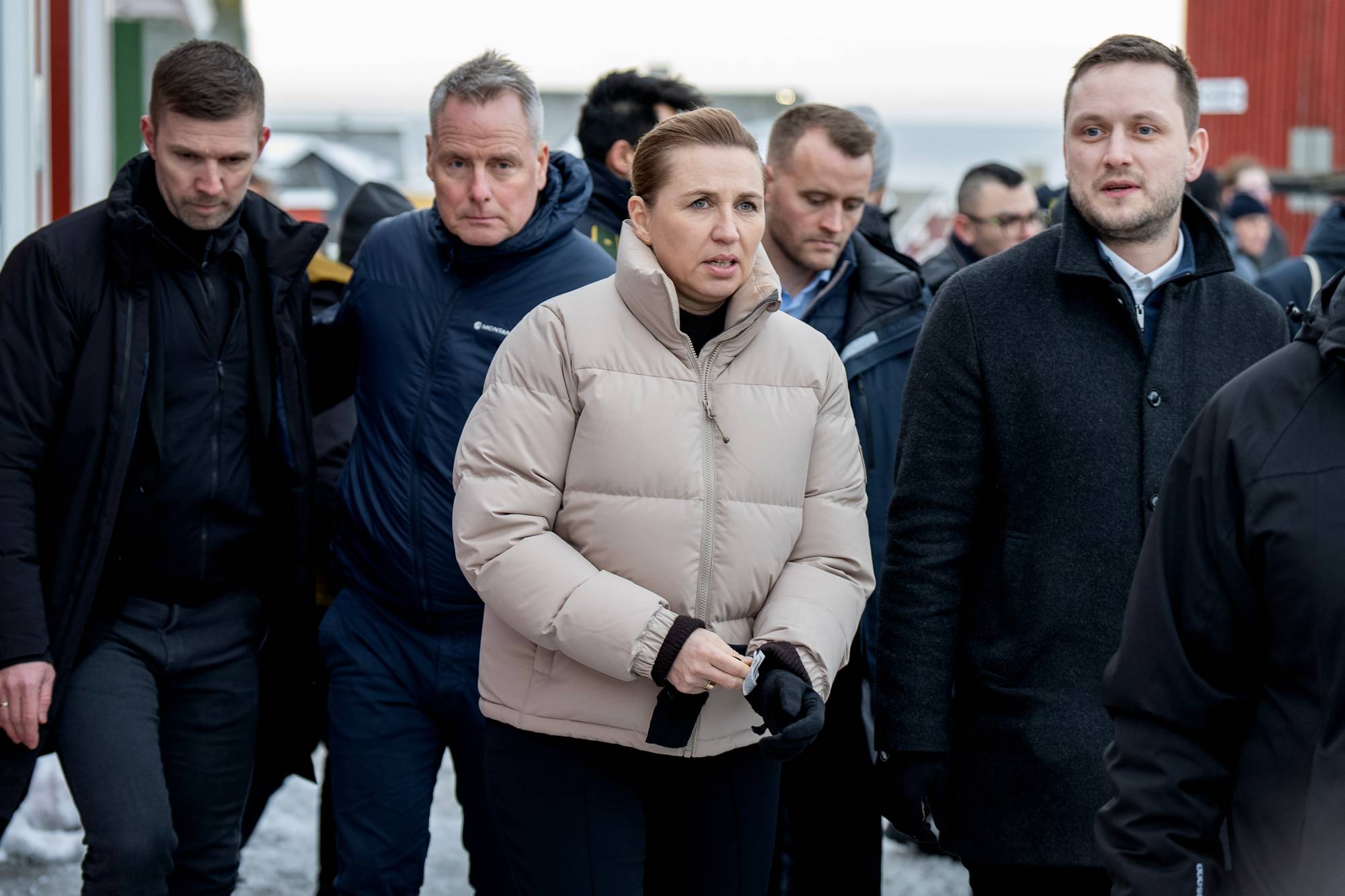 Grønlands statsminister og Danmarks statsminister går ute på gaten sammen, med en stor mengde journalister rundt dem. 