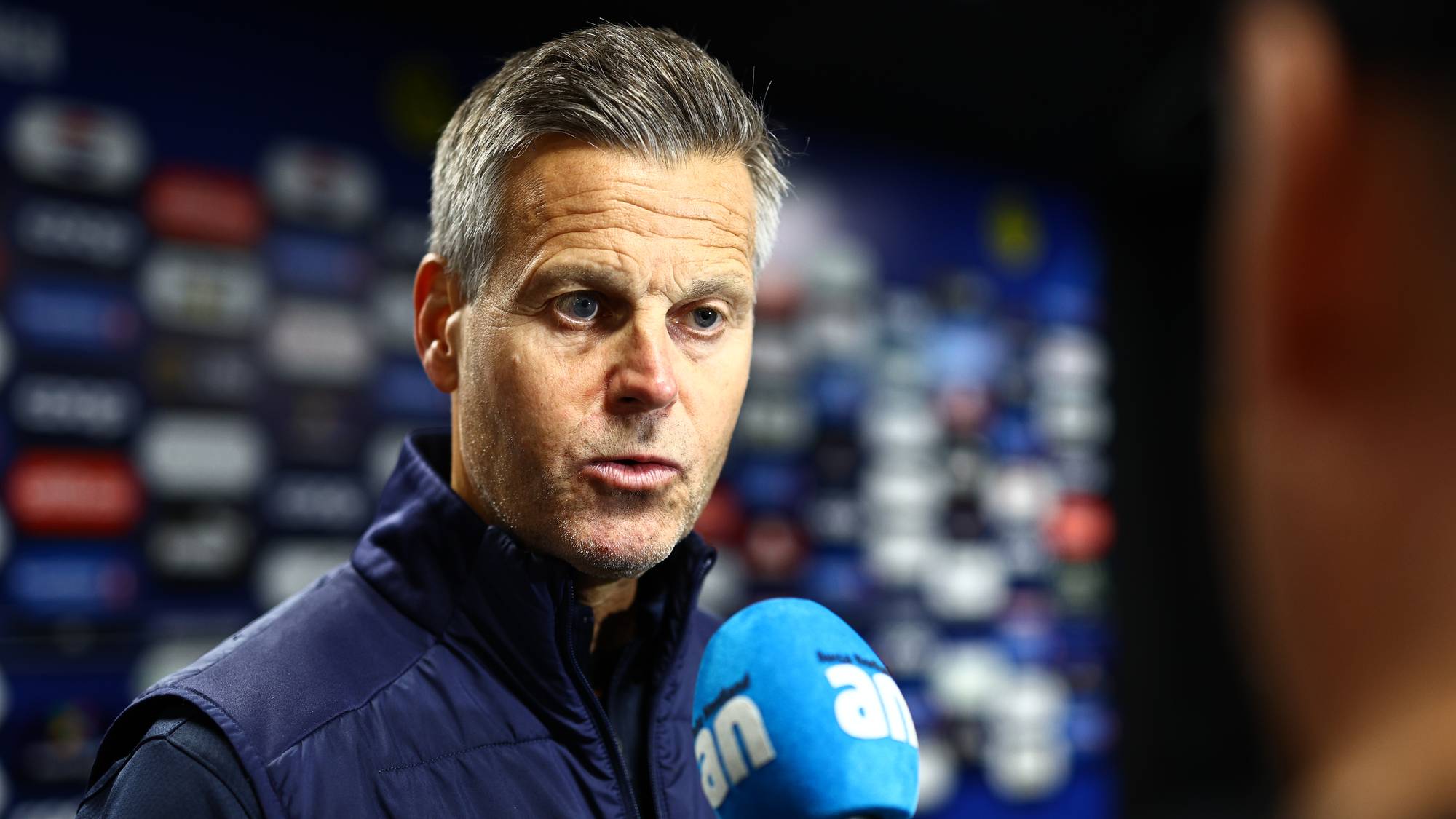 Kjetil Knutsen blir intervjuet foran en bakvegg med logoer. (Bildebeskrivelsen er laget av en KI-tjeneste)
