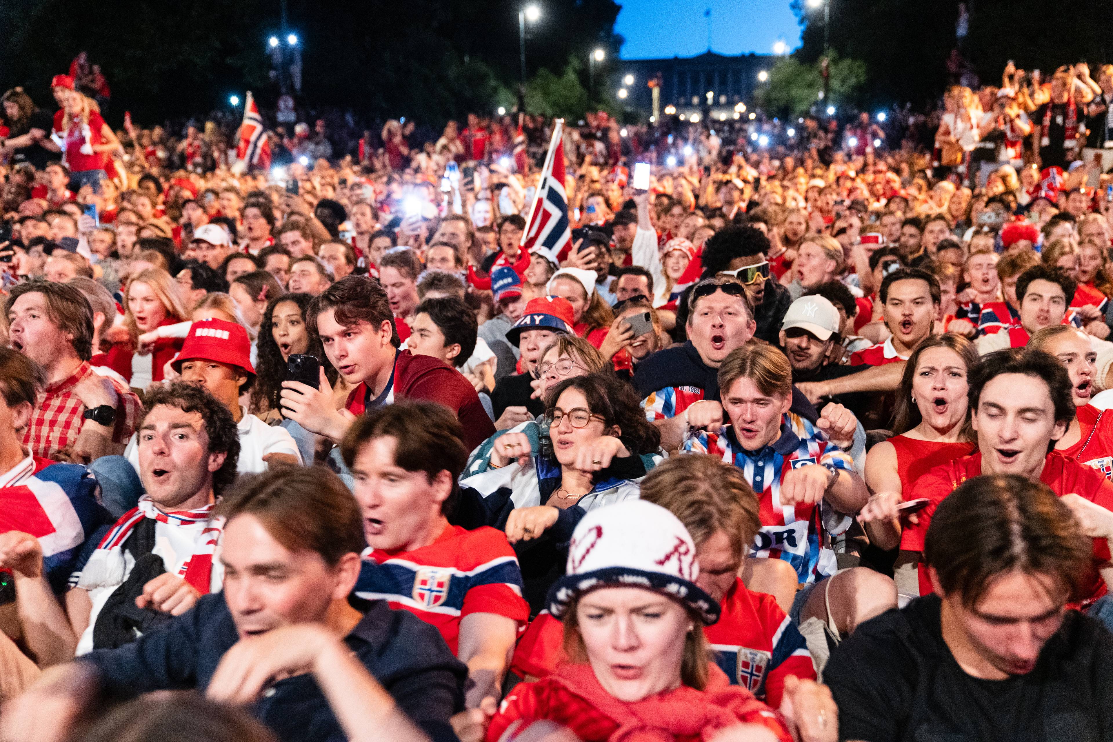 Menneskemengde samlet utendørs for å se kamp, mange har på seg norske flagg og supporterutstyr.