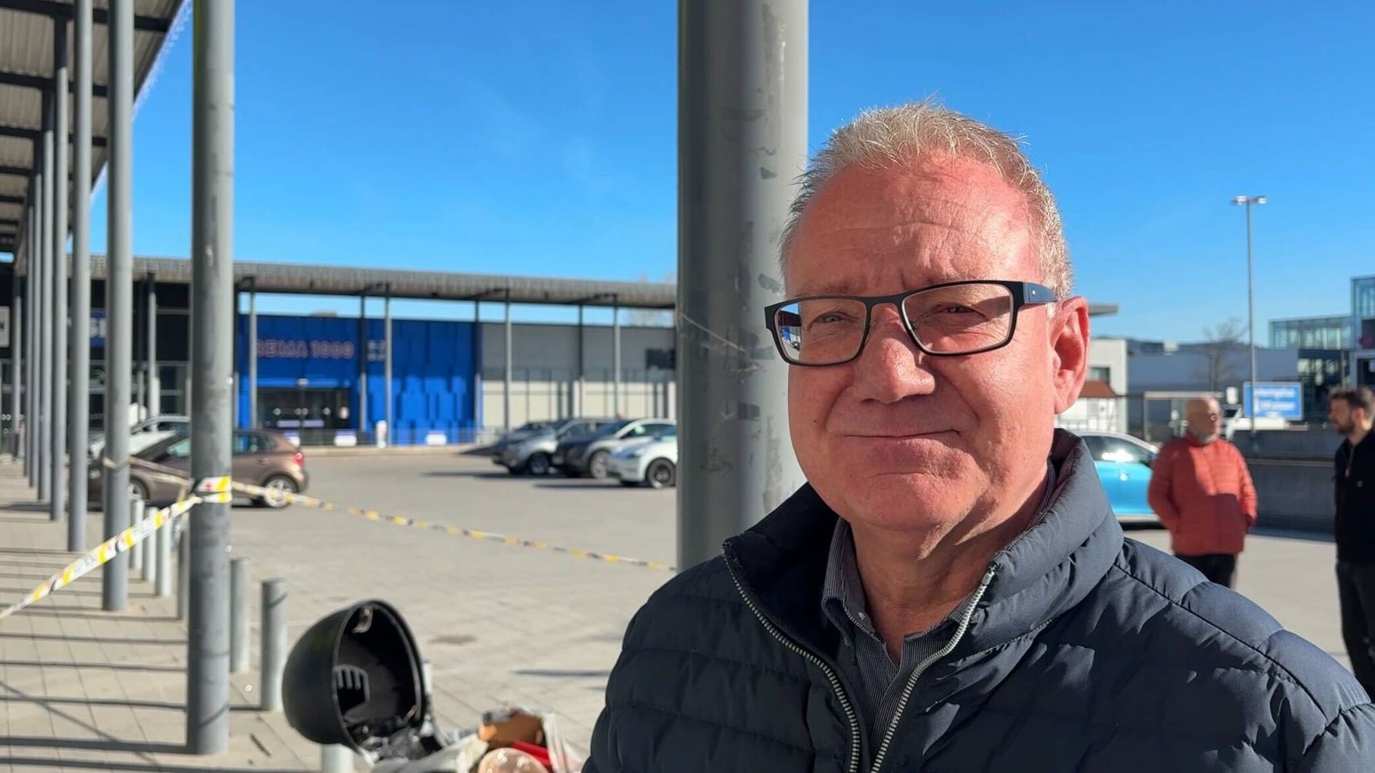 En mann står foran en politisperring utenfor et kjøpesenter.