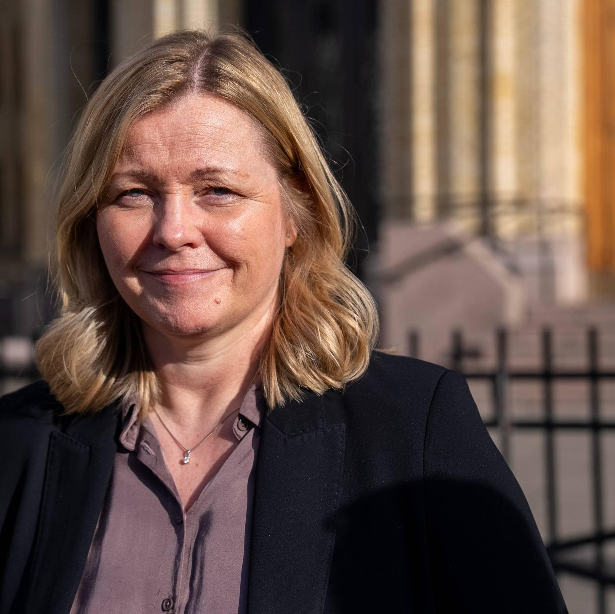en kvinne med blondt hår i skjorte og blazer foran stortinget