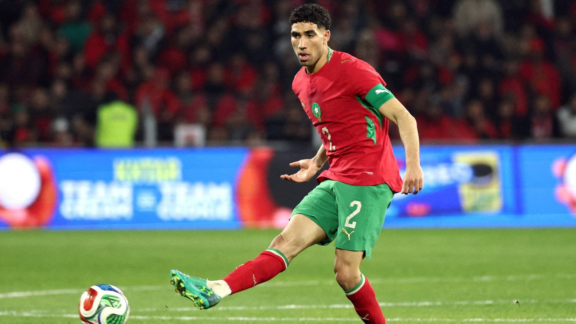 Fotballspiller Achraf Hakimi i Marokkos drakt scorer mål.
Han er på en fotballbane og har publikum i bakgrunnen.
Hakimi spiller for Paris Saint-Germain.
(Bildebeskrivelsen er laget av en KI-tjeneste)