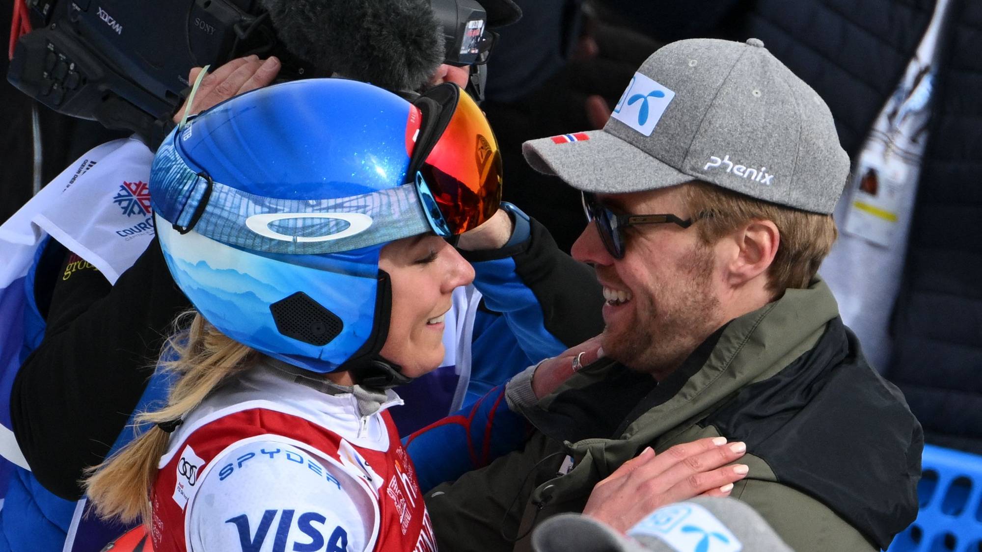 En kvinnelige alpinist med hjelm og en mann med cap smiler mot hverandre
