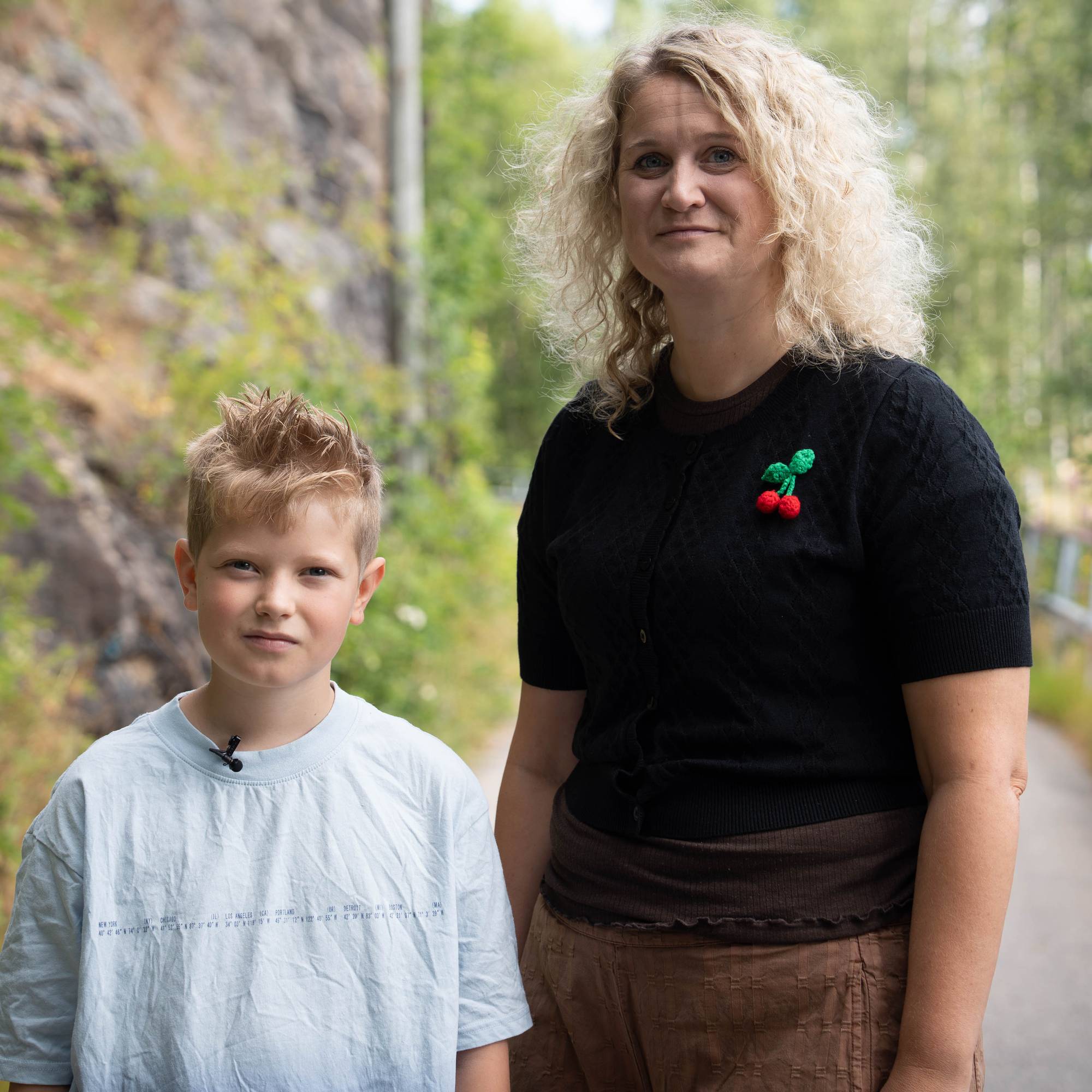En person og en gutt står på en sti i skogen (Bildebeskrivelsen er laget av en KI-tjeneste)