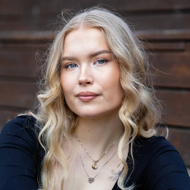 Ingeborg Grønnesby (20) har lange blonde krøller og midtskill. Hun har på seg en sort genser og halskjeder. Hun har et mykt blikk og et seriøst uttrykk.
