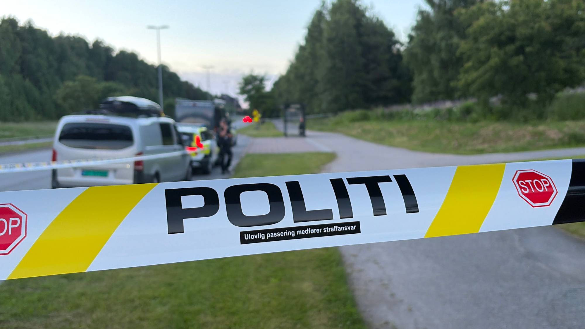 Politiet har sperret av et område med biler i bakgrunnen. (Bildebeskrivelsen er laget av en KI-tjeneste)
