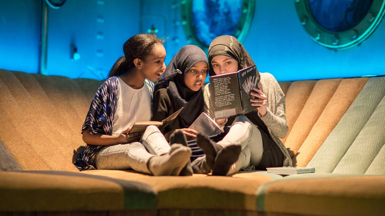 Tre jenter leser bok på Biblio Tøyen