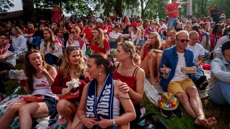 Folk sitter på tepper i en park og spiser og drikker under utendørsarrangement. (Bildebeskrivelsen er laget av en KI-tjeneste)