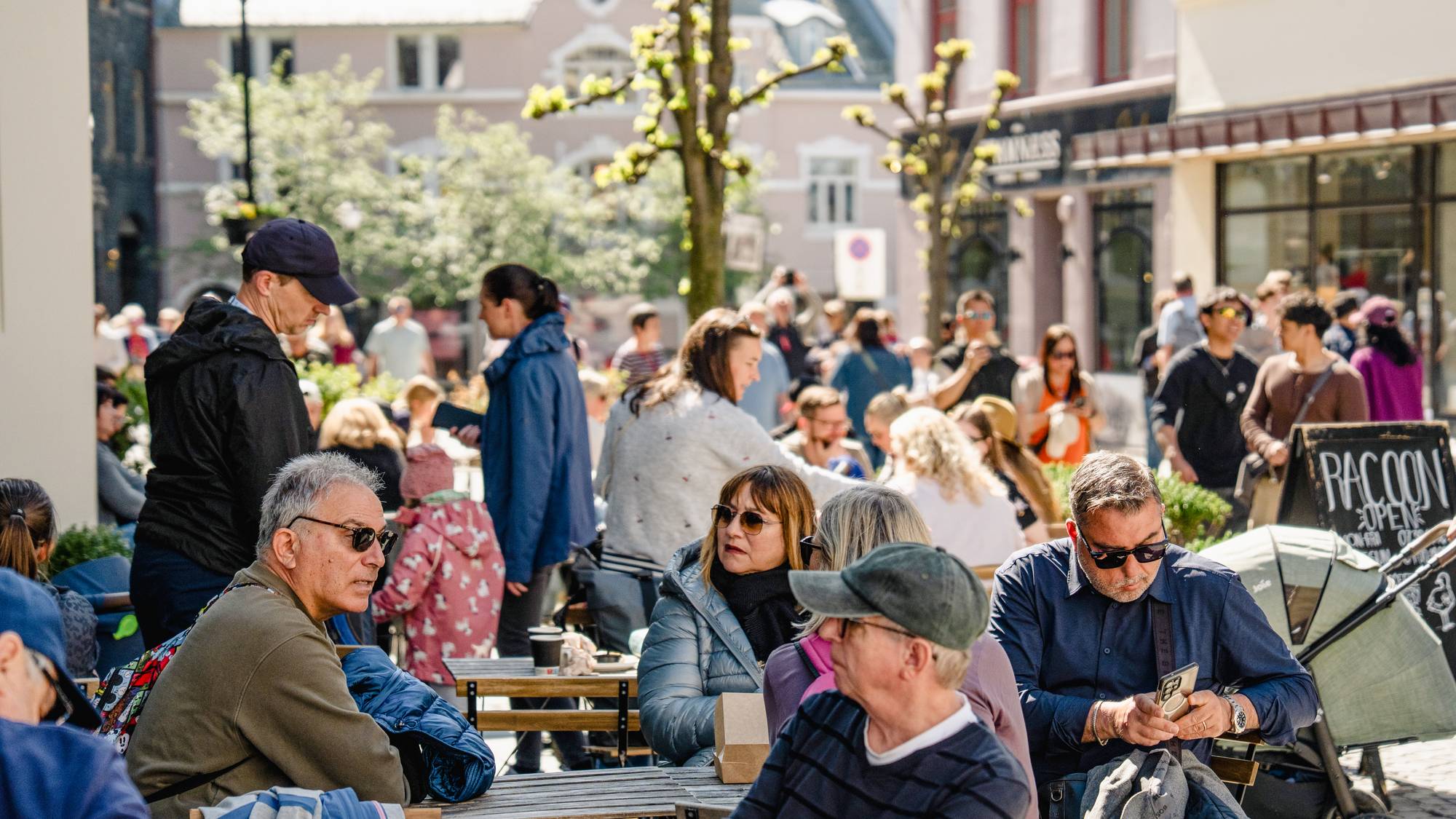 Mange cruiseturister i Ålesund da AidaNova og MSC Euribia dro med seg ca 12.000 passasjerer til byen. Sarah Soumilas eier kafeen Racoon i Kongens gate i Ålesund og er glad for omsetningen cruisepassasjerene gir. Det er stor aktivitet på kafeen.