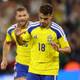 JULIO CESAR AGUILAR / AFP,NTB Two Swedish football players in yellow jerseys with blue trim stand on a field. The player in the foreground, wearing number 18, raises his hand. Behind him, another player in a similar jersey smiles. The background shows blurred spectators in a stadium. (Bildebeskrivelsen er laget av en KI-tjeneste)