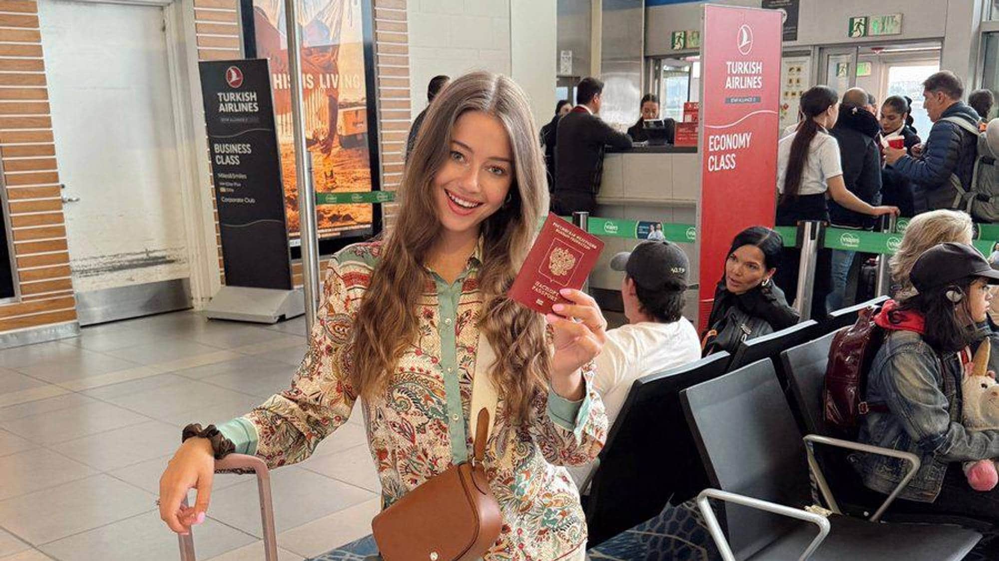 Kvinne med rosa trillekoffert inne på en flyplass