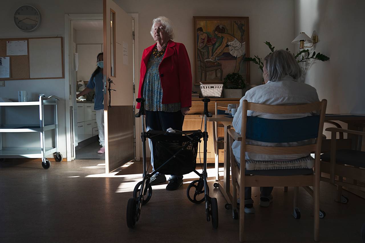 Anne Marie står rakrygget opp ved siden av frokostbordet i sin røde jakke