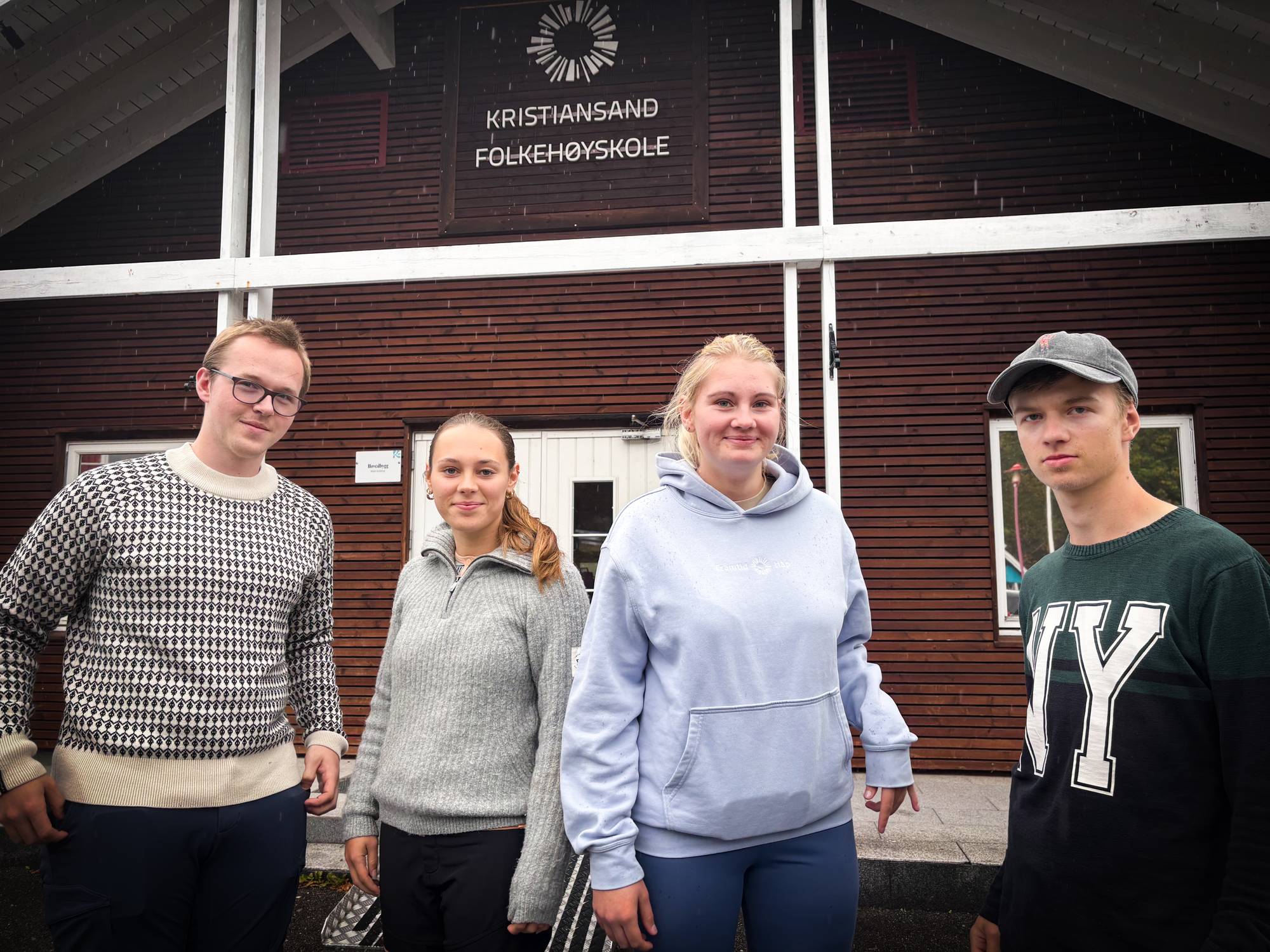 Fire unge står foran inngangen til Kristiansand folkehøyskole. (Bildebeskrivelsen er laget av en KI-tjeneste)
