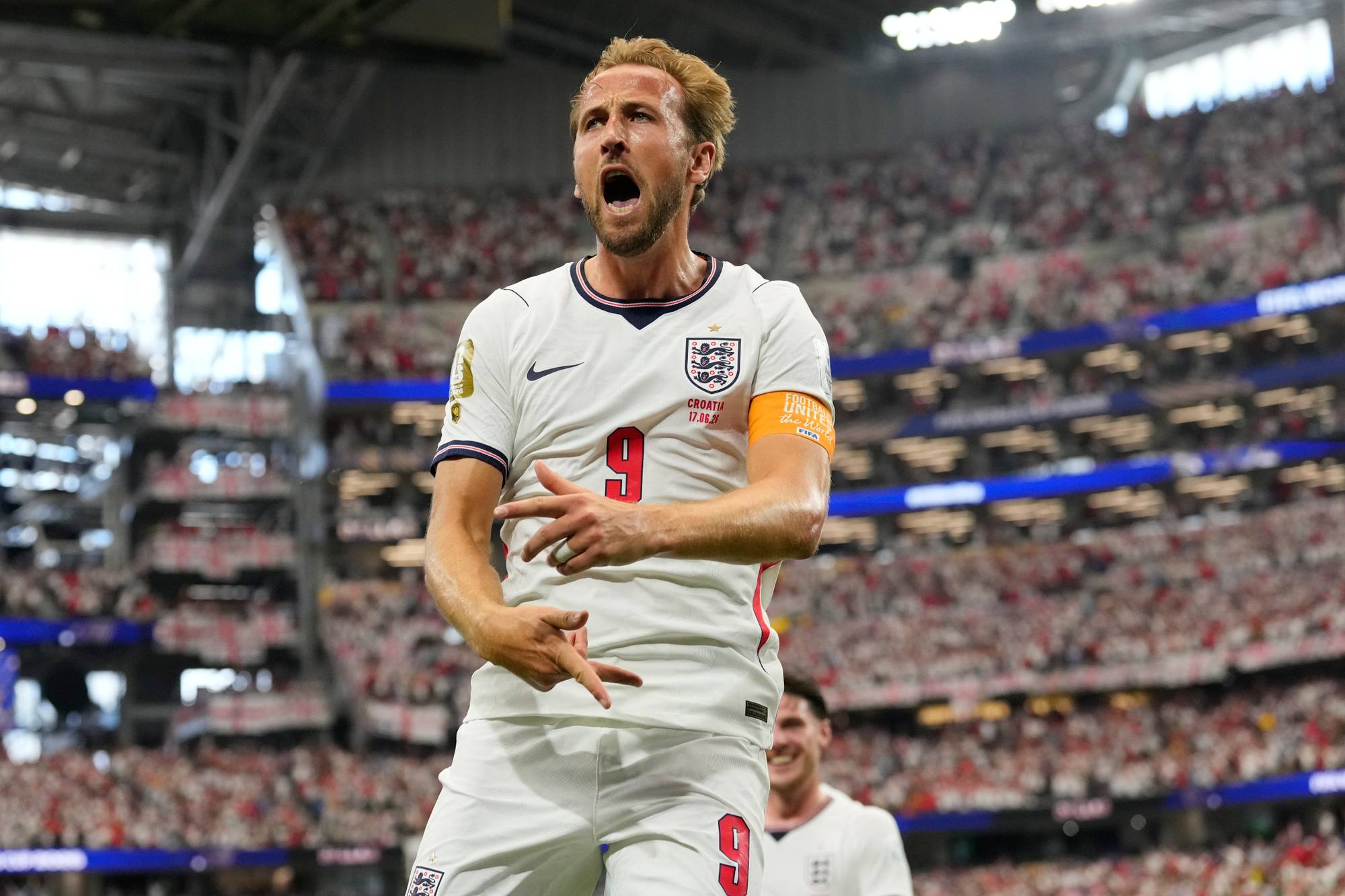 Harry Kane jubler i hvit landslagsdrakt foran publikum på en fotballstadion. (Bildebeskrivelsen er laget av en KI-tjeneste)