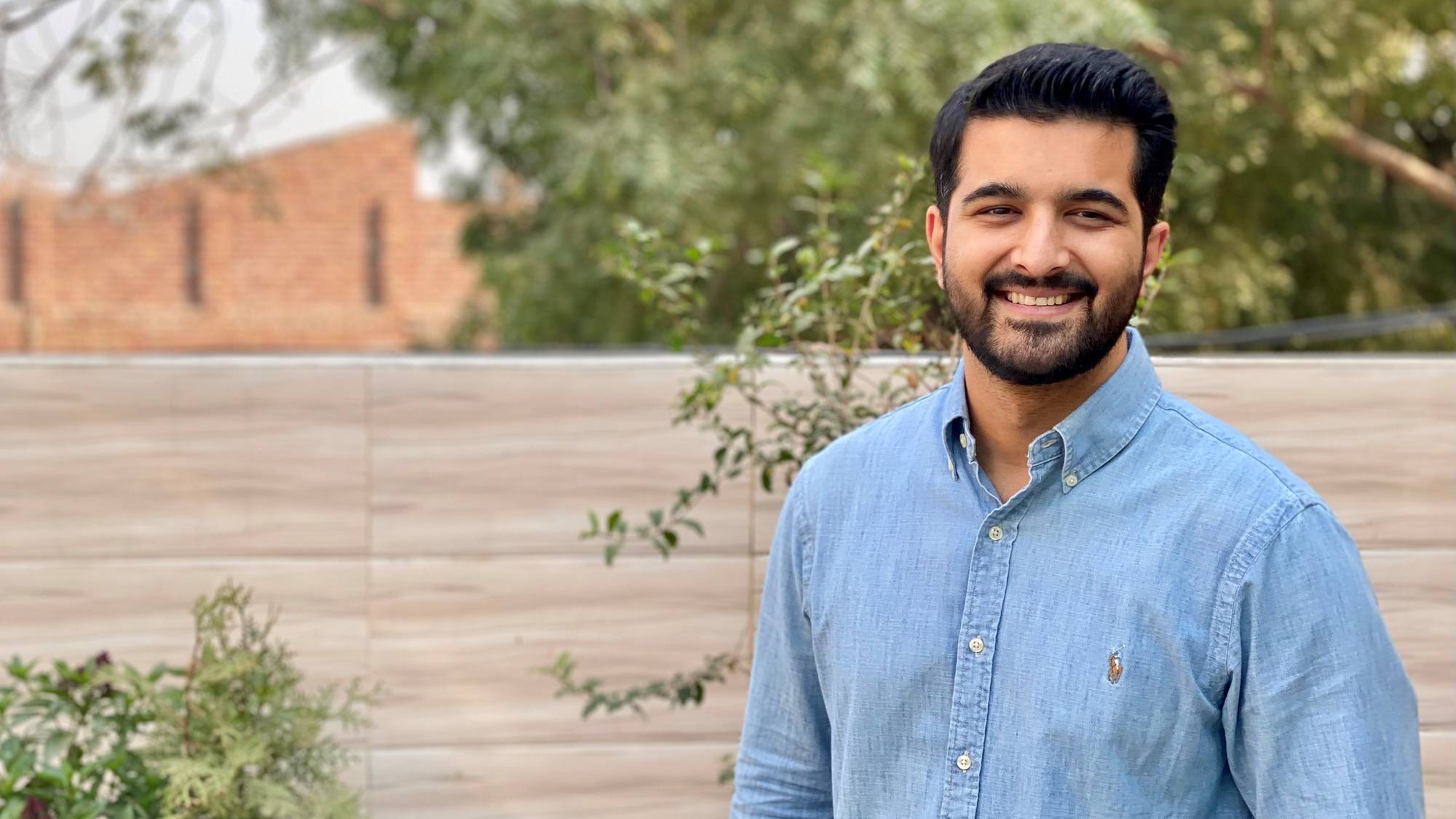 Ung, velstelt pakistansk mann med kort mørkt hår smiler mot kamera. Han har på seg en blå jeansskjorte. Mannen er Usman Chaudhry. Han er psykolog ved Rask Psykisk Helsehjelp på Stovner. 