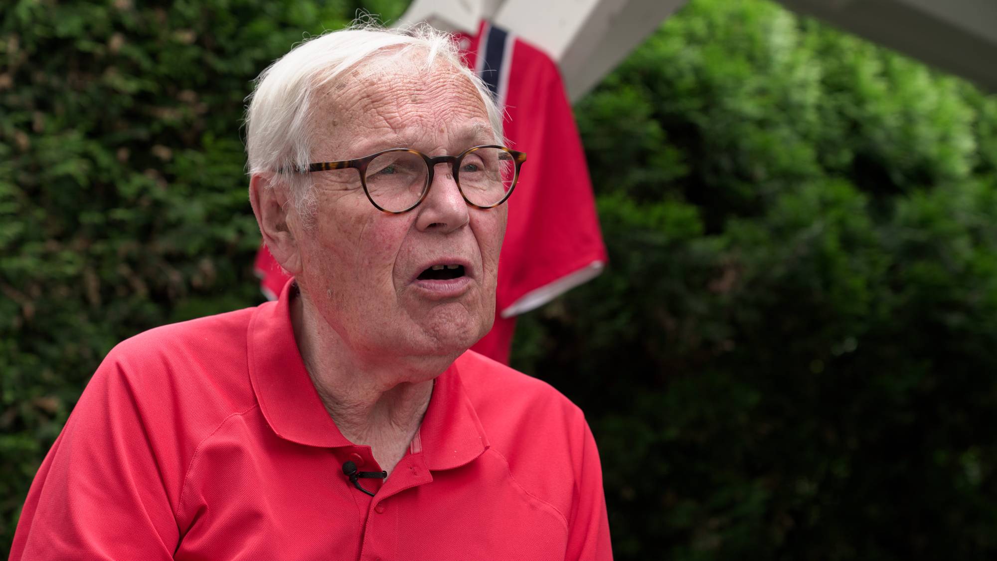 Arne Scheie som gir et sittende intervju med Norges fotballdrakt i bakgrunn. 