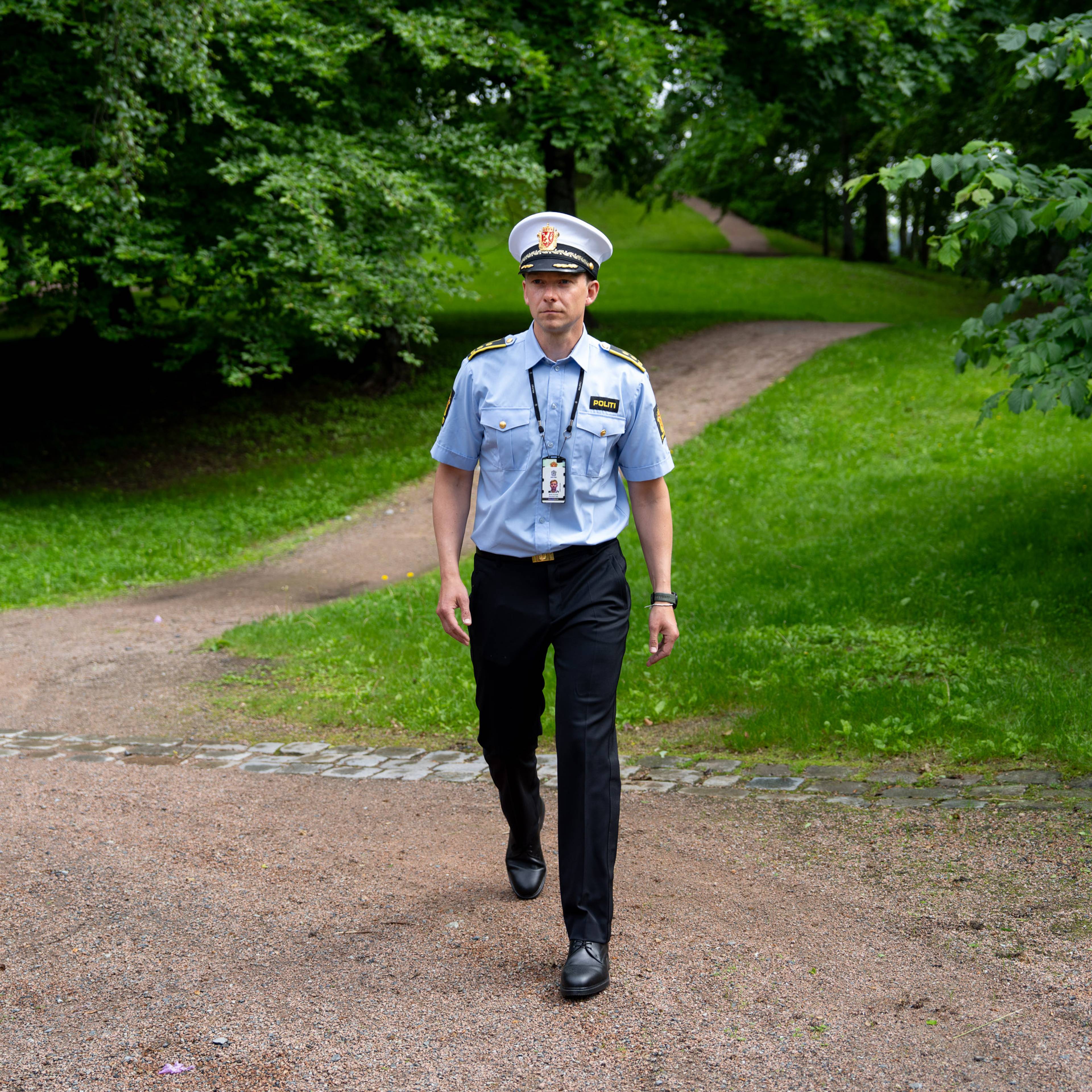 Politiadvokat Henrik Horverak Steenfeldt-Foss går ute i et grønt område i Sandvika. Han har på seg politiuniform og hatt.