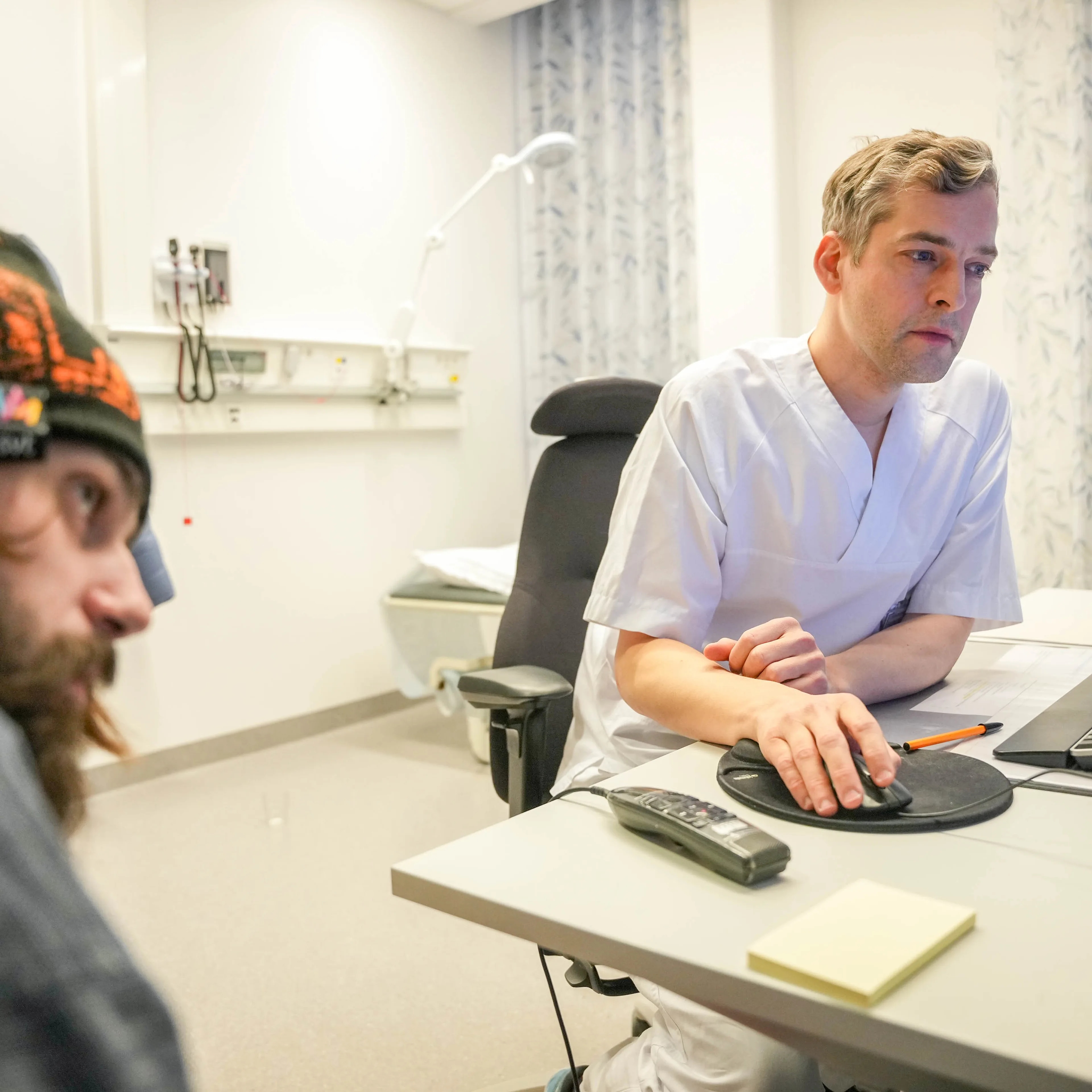 to menn som sitter ved et bord og ser på en datamaskin