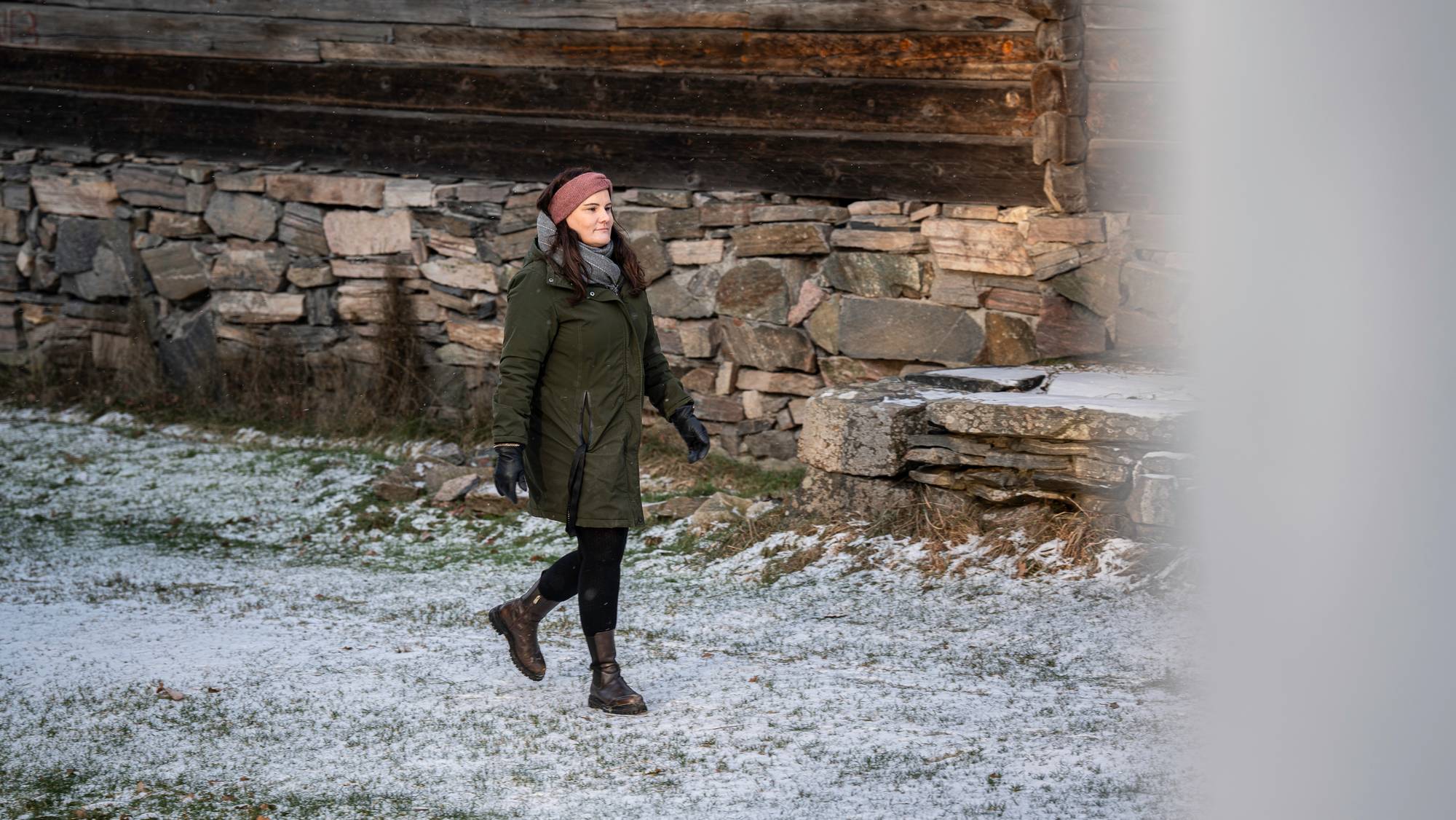 Kvinne går ved en gammel gård. 