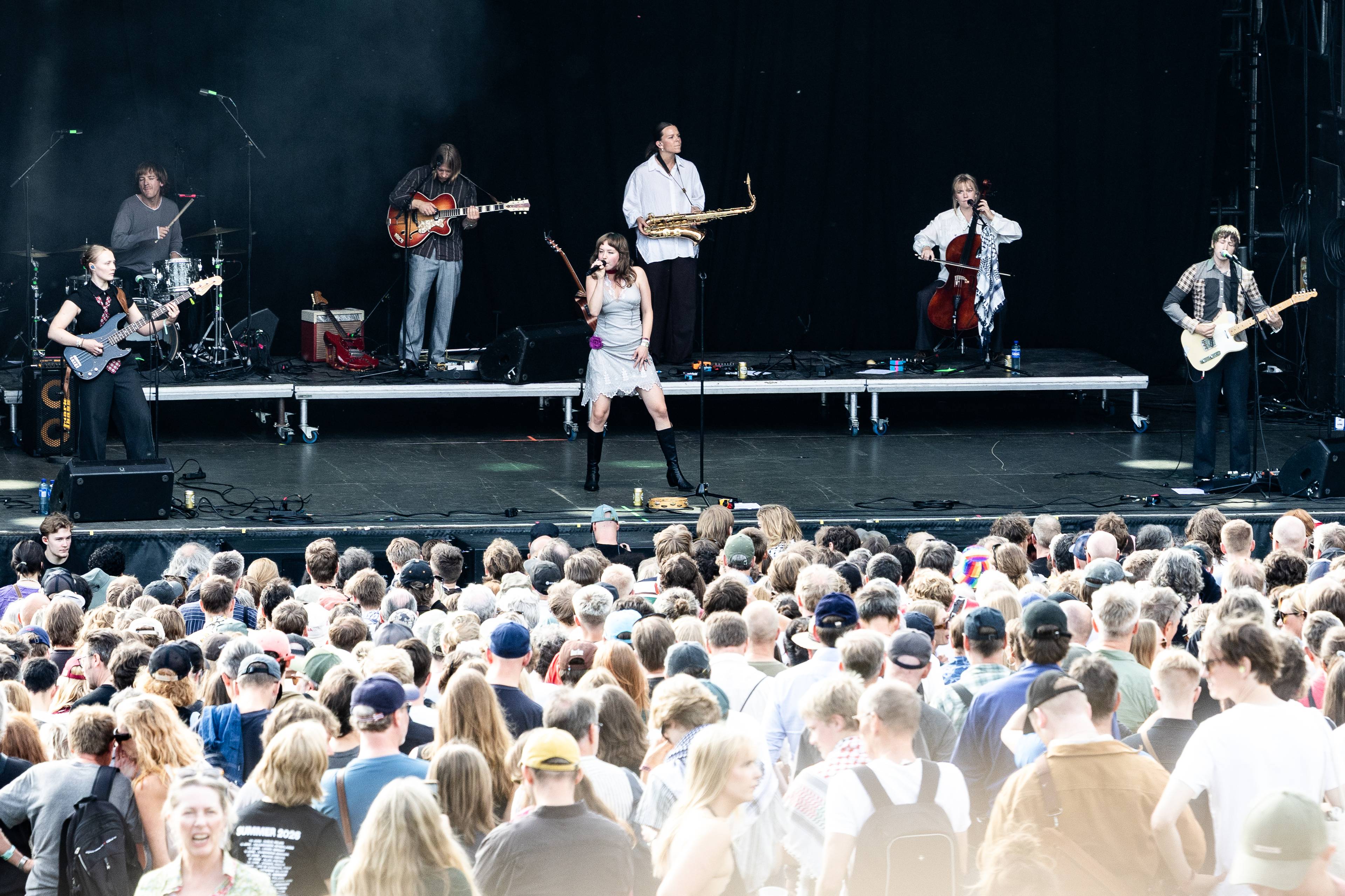Band opptrer på en utendørs scene foran et stort publikum.