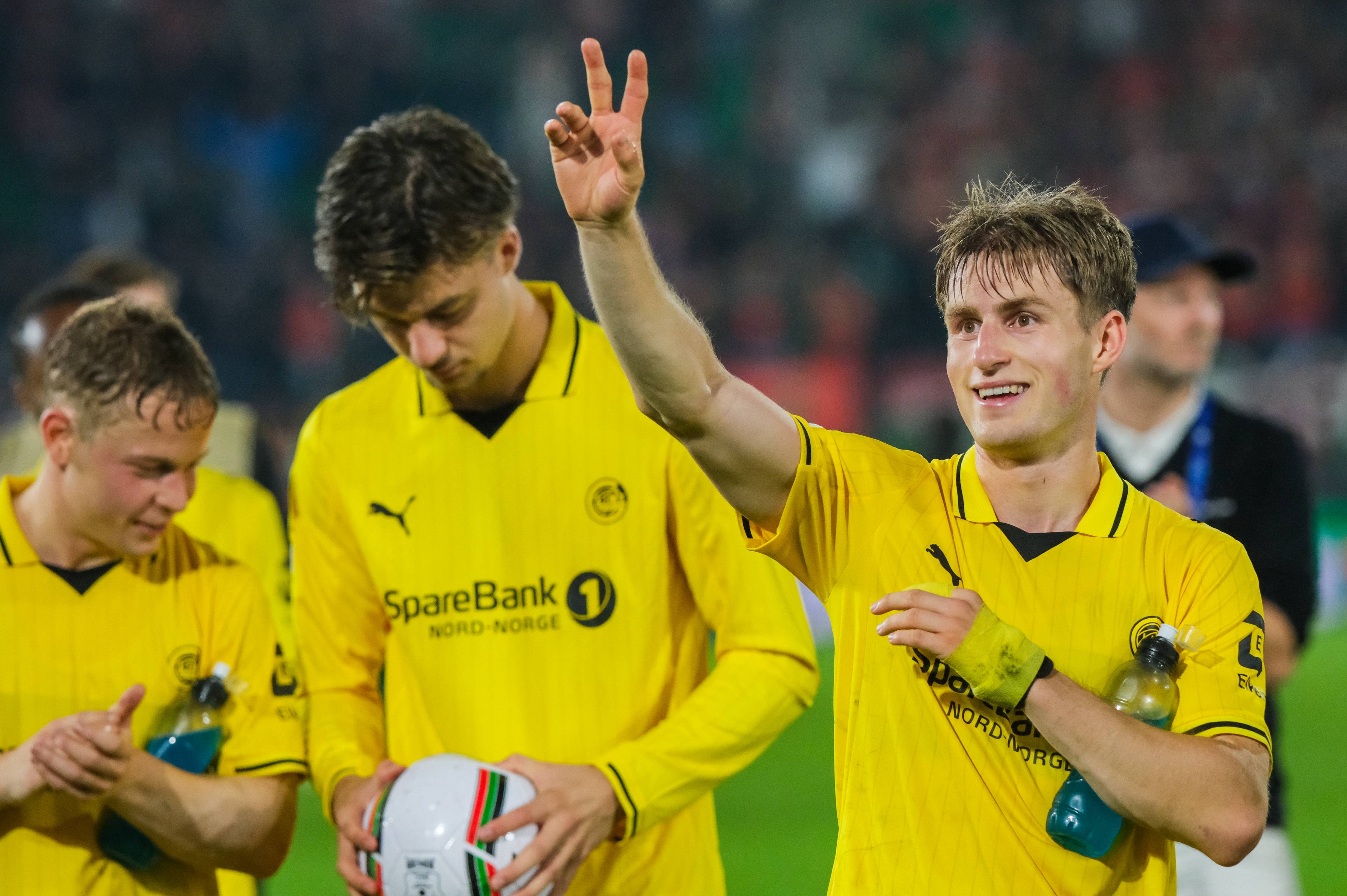 Fotballspiller i gul drakt viser tre fingre med hånden hevet etter en kamp på en stadion. (Bildebeskrivelsen er laget av en KI-tjeneste)