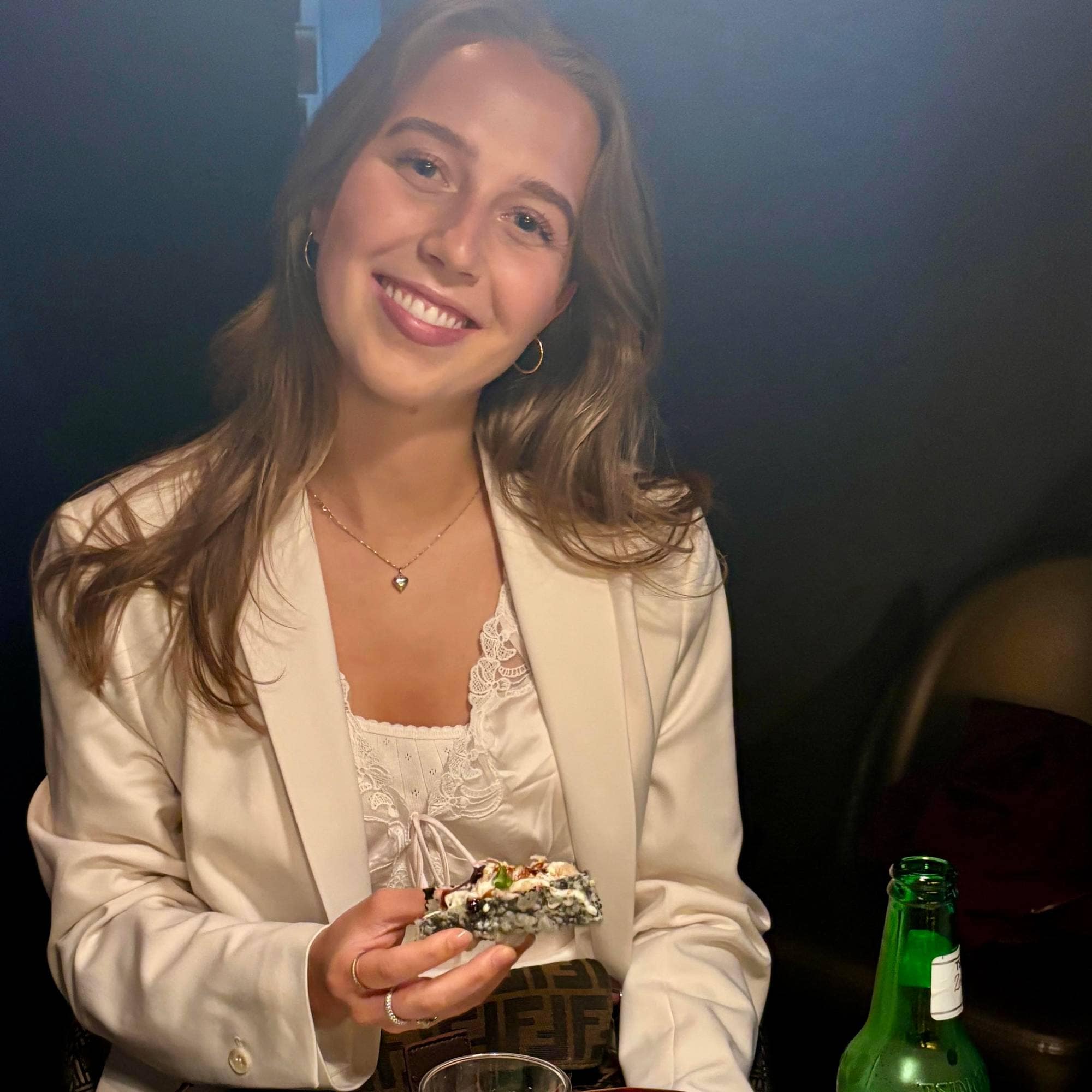 Ung dame i hvit blazer spiser middag på restaurant.