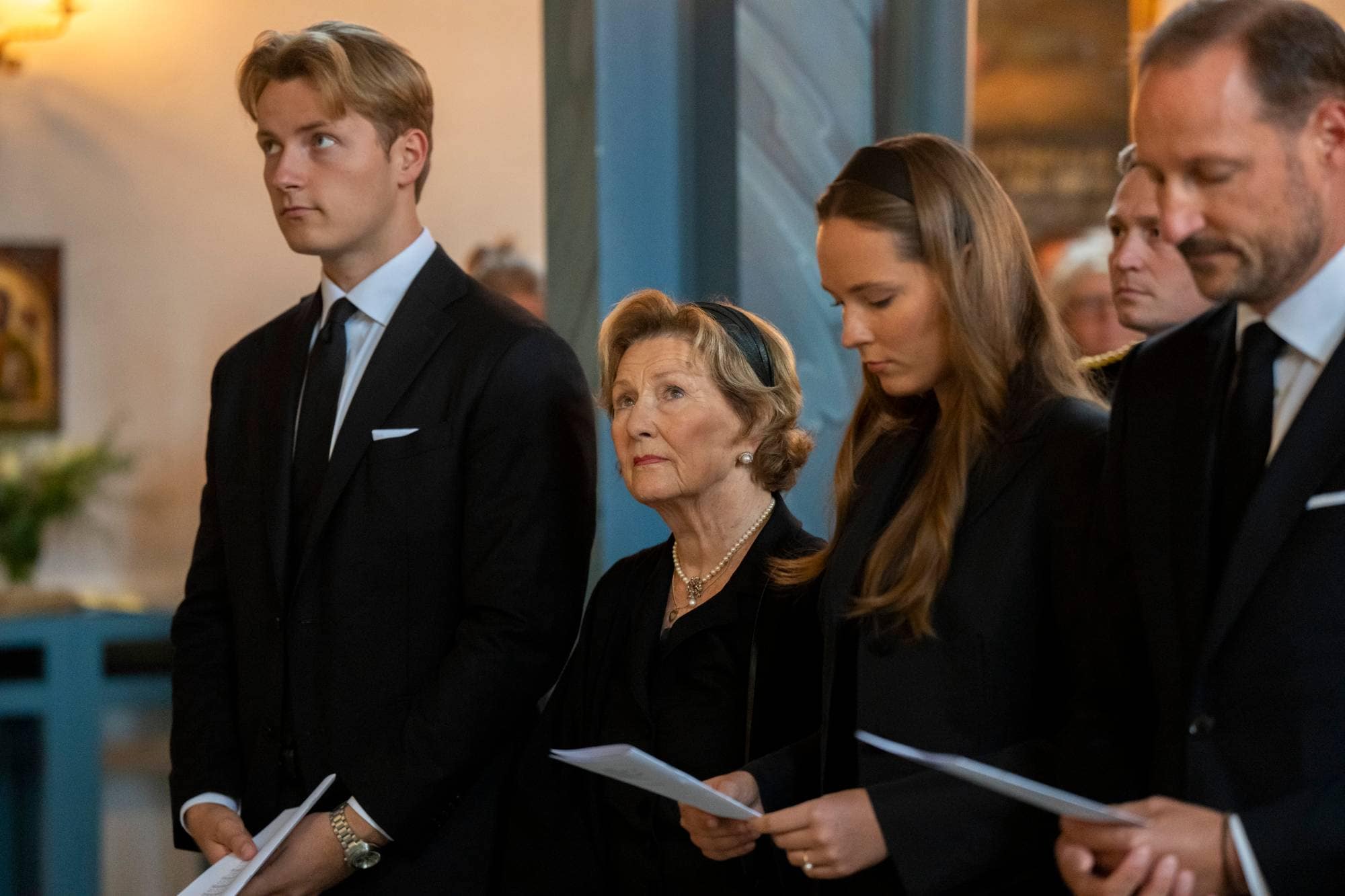 Dronning Sonja i Asker kirke. Hun er kledd i sort og omgitt av familien.