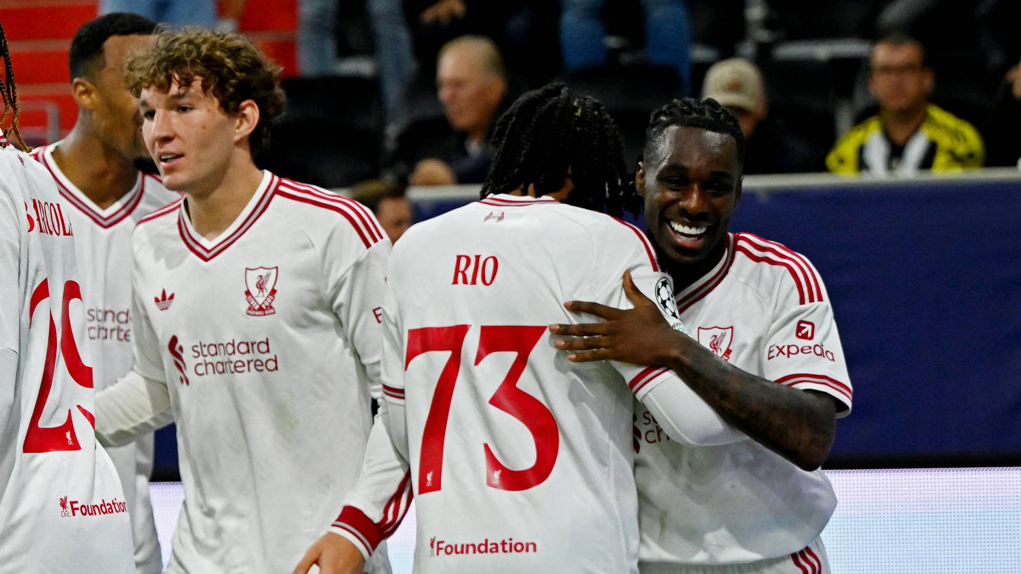 Liverpool-spillere jubler sammen i hvite drakter på en fotballbane. (Bildebeskrivelsen er laget av en KI-tjeneste)
