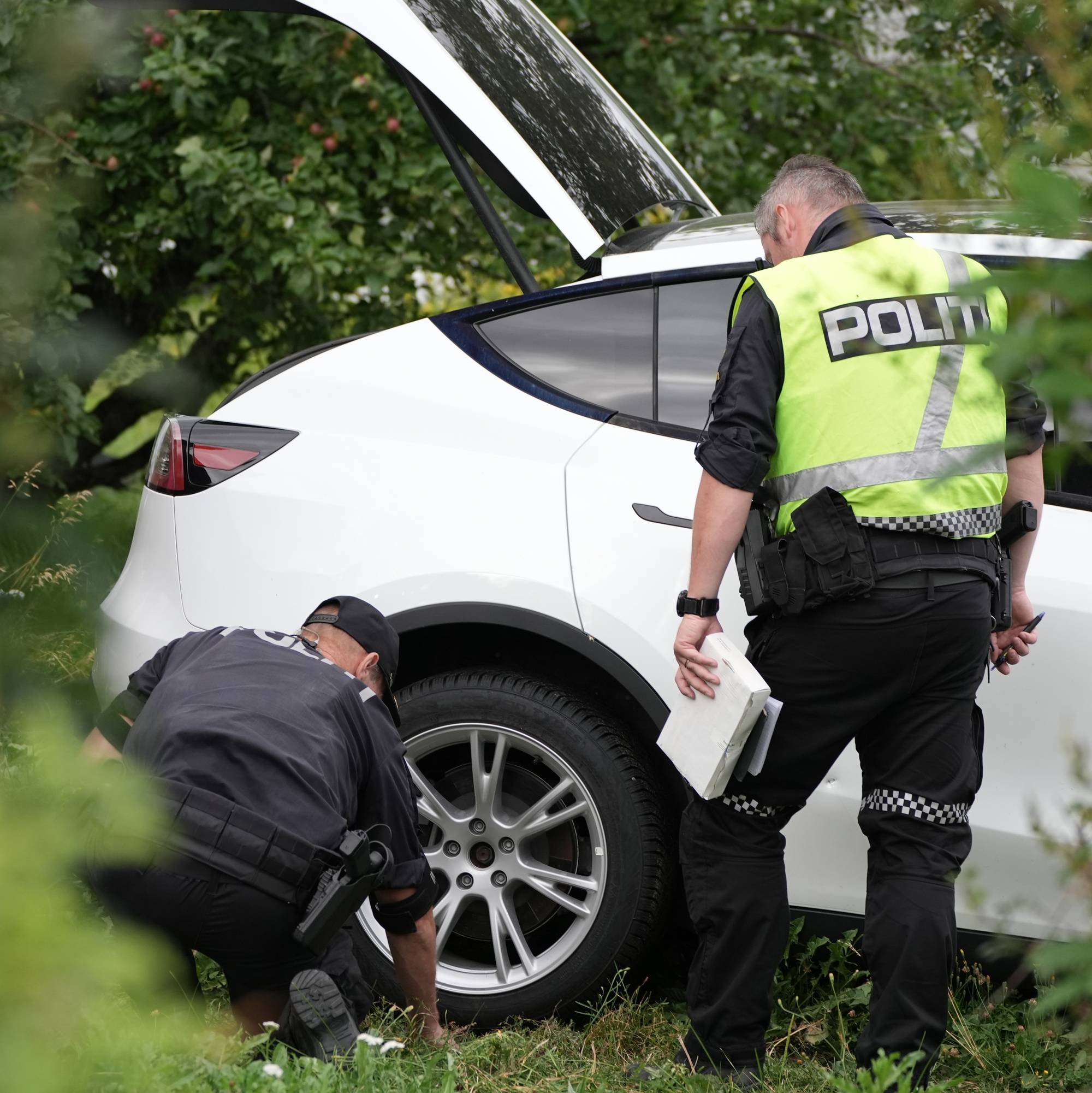 To politipatruljer som sjekker ut en hvit bil. 