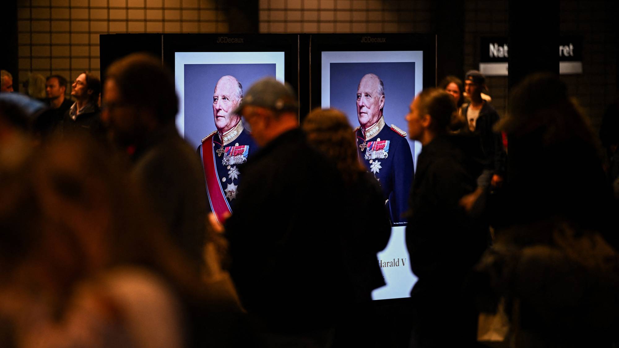 Bilde av kong Harald fyller to store skjermer på Nationaltheatret t-banestasjon i Oslo
