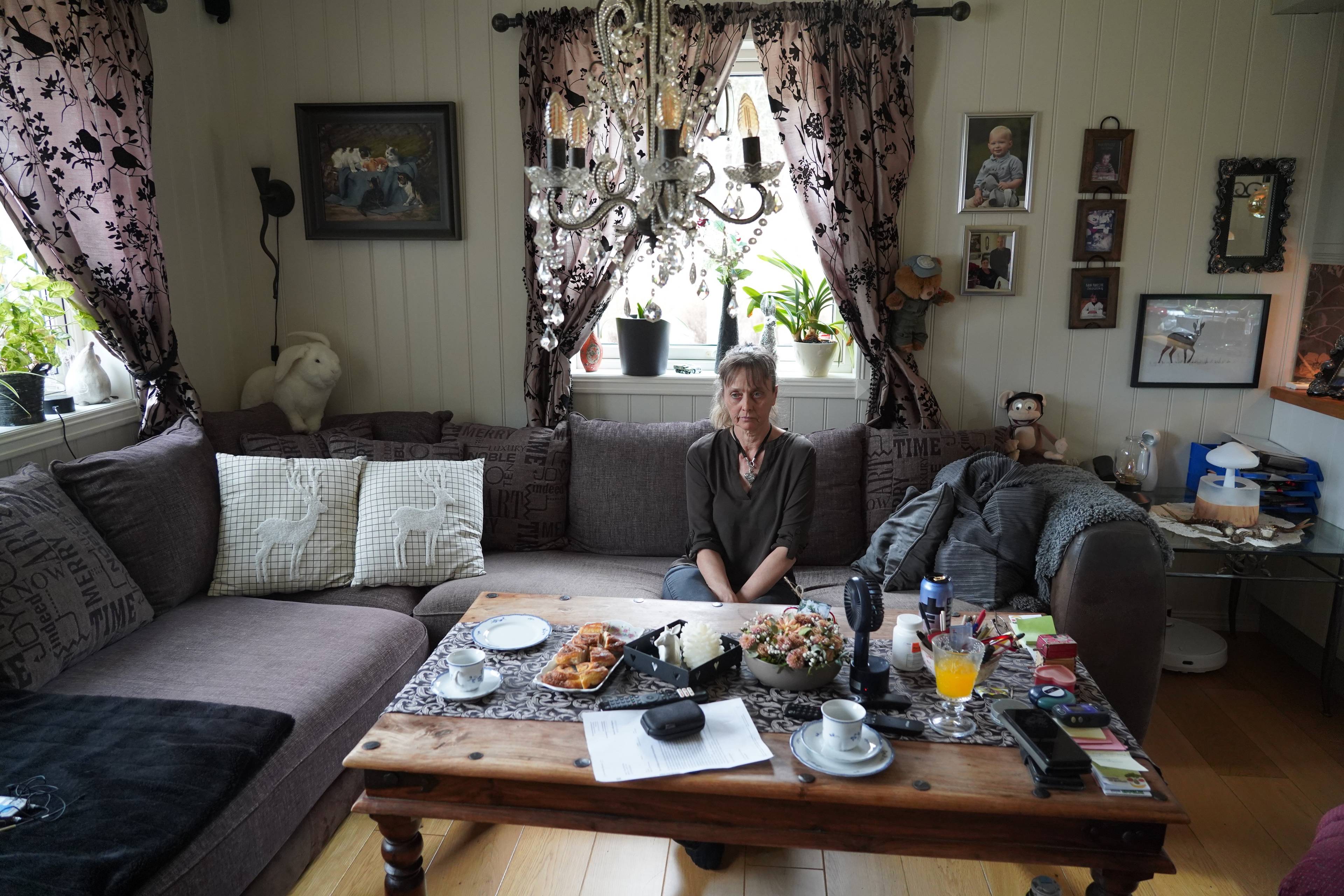 En kvinne sitter i en sofa i et hus