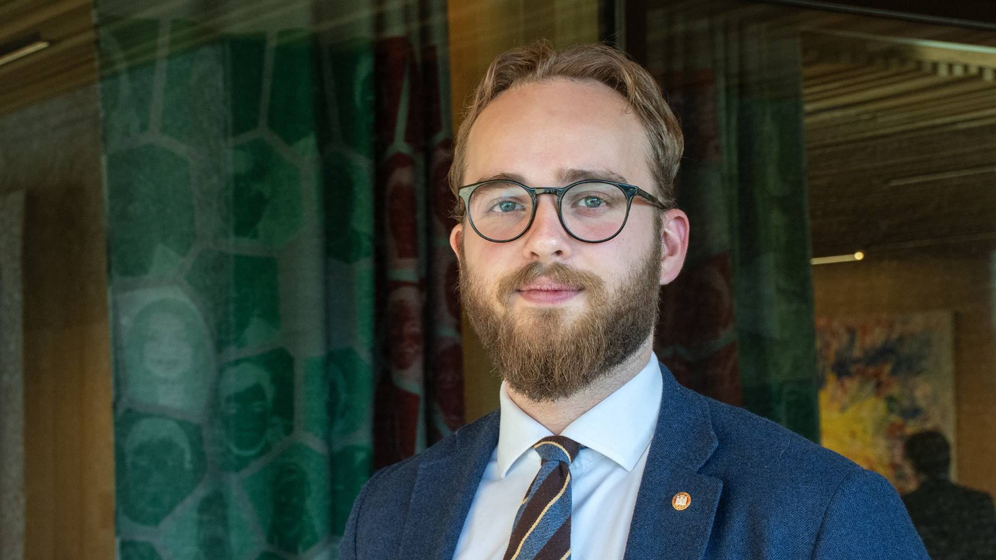 Mann i dress ser inn i kamera.